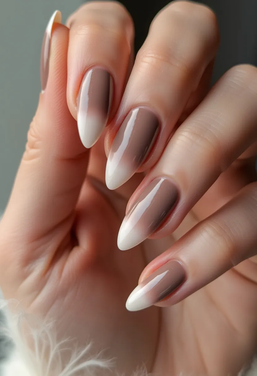 The nail design features a sophisticated gradient color palette ranging from a soft taupe at the base to a milky white at the tips, creating a seamless ombre effect. The nails are shaped with a sharp, stiletto-like point, adding a sleek and edgy vibe to the overall look. This design appears to use gel treatment, given the smooth and glossy finish that is characteristic of gel nails. The simplicity and elegance of the gradient make this design versatile for multiple occasions, including formal events or seasonal transitions, particularly suitable for autumn or winter with its muted and chic tones. No additional intricate patterns or decorations are present, allowing the gradient and shape to be the focal points of this striking manicure.