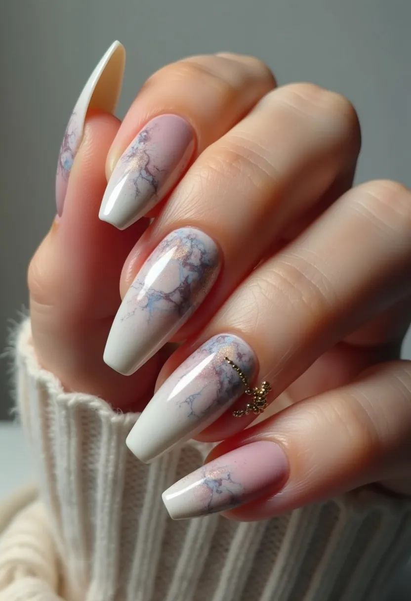 The nail design features an elegant and intricate look with a soft and muted color palette, predominantly using shades of white, light pink, and hints of blue-gray. The nails are crafted into a medium-length almond shape, providing a sophisticated base for the design. Each nail showcases a marbled pattern that integrates the light pink and blue-gray hues, creating a delicate, cloud-like effect. Additionally, there is a subtle touch of shimmering gold running through the marble design, adding a hint of glamor. One nail on each hand is adorned with a small, golden bead arrangement, giving the design a luxurious touch. This nail art appears to be done with gel polish, ensuring a glossy and durable finish. The overall aesthetic is chic and versatile, suitable for both everyday wear and special occasions, and it could particularly complement winter or festive themes.