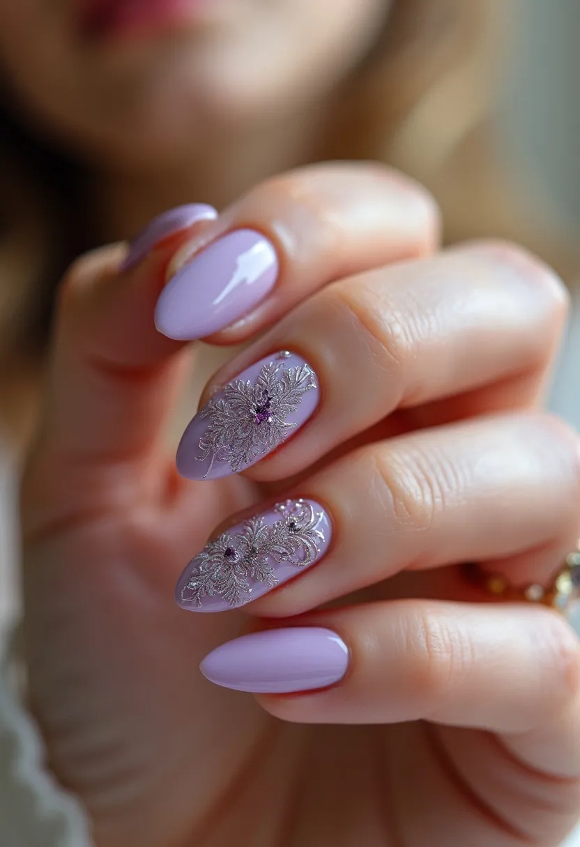 This nail design features a beautiful pastel lavender color palette, enhancing the elegance of the almond-shaped nails. The nails are meticulously maintained with a glossy finish suggestive of a gel or shellac treatment, offering both durability and shine. Two of the nails are adorned with intricate floral patterns, incorporating delicate silvery designs and small purple rhinestones at the center, adding a touch of sophistication and glamour to the overall look. The detailed decorations and the pastel hue suggest a theme that could be ideal for spring or a special occasion like a wedding or formal event, evoking a sense of freshness and grace.