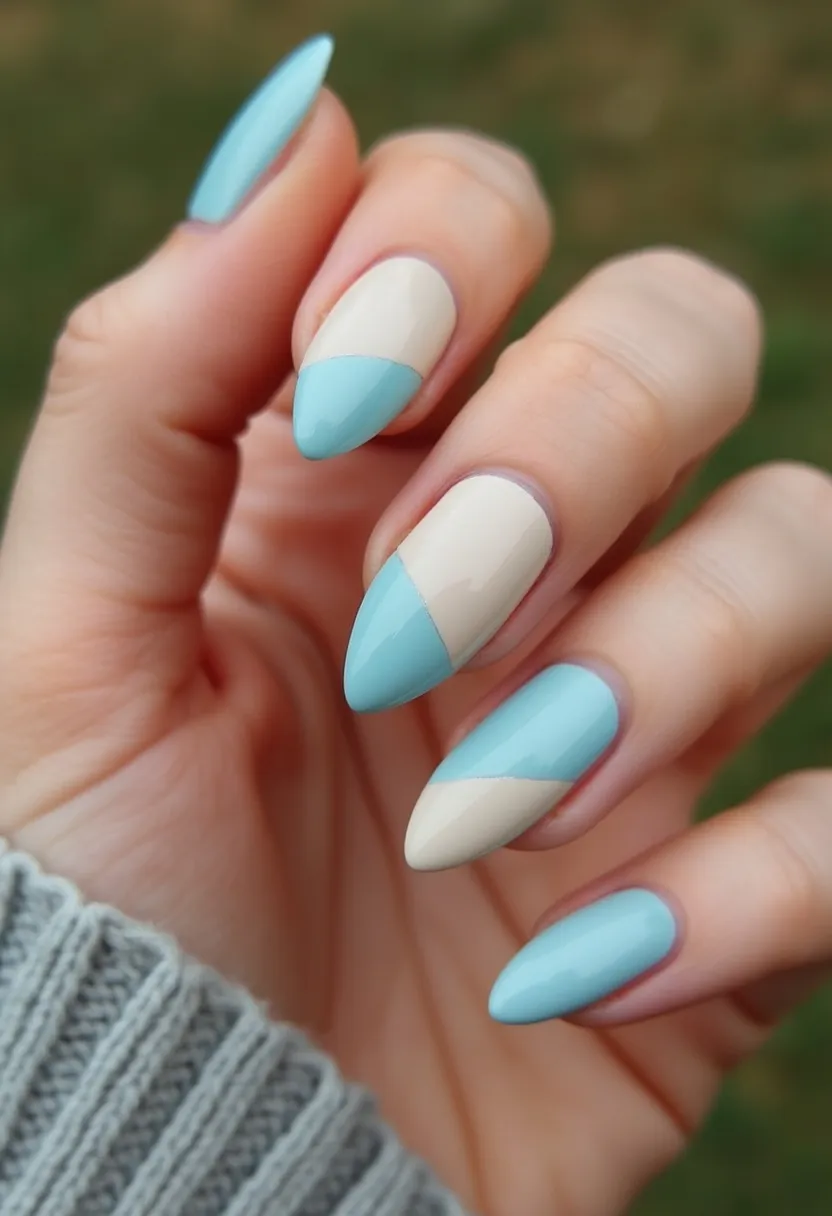 The nail design features a sophisticated and elegant color palette comprising light blue and nude shades. The nails have an almond shape, giving a sleek and feminine look. Each nail displays a stylish, diagonal color-blocking pattern where the light blue and nude shades intersect, creating a visually appealing and modern aesthetic. The nail treatment appears to be a glossy finish, suggesting either gel or shellac application, giving the nails a smooth and shiny appearance. This design could be suitable for any special occasion, and while it is not explicitly seasonal, its soft colors and refined look make it versatile enough for both casual and formal settings.