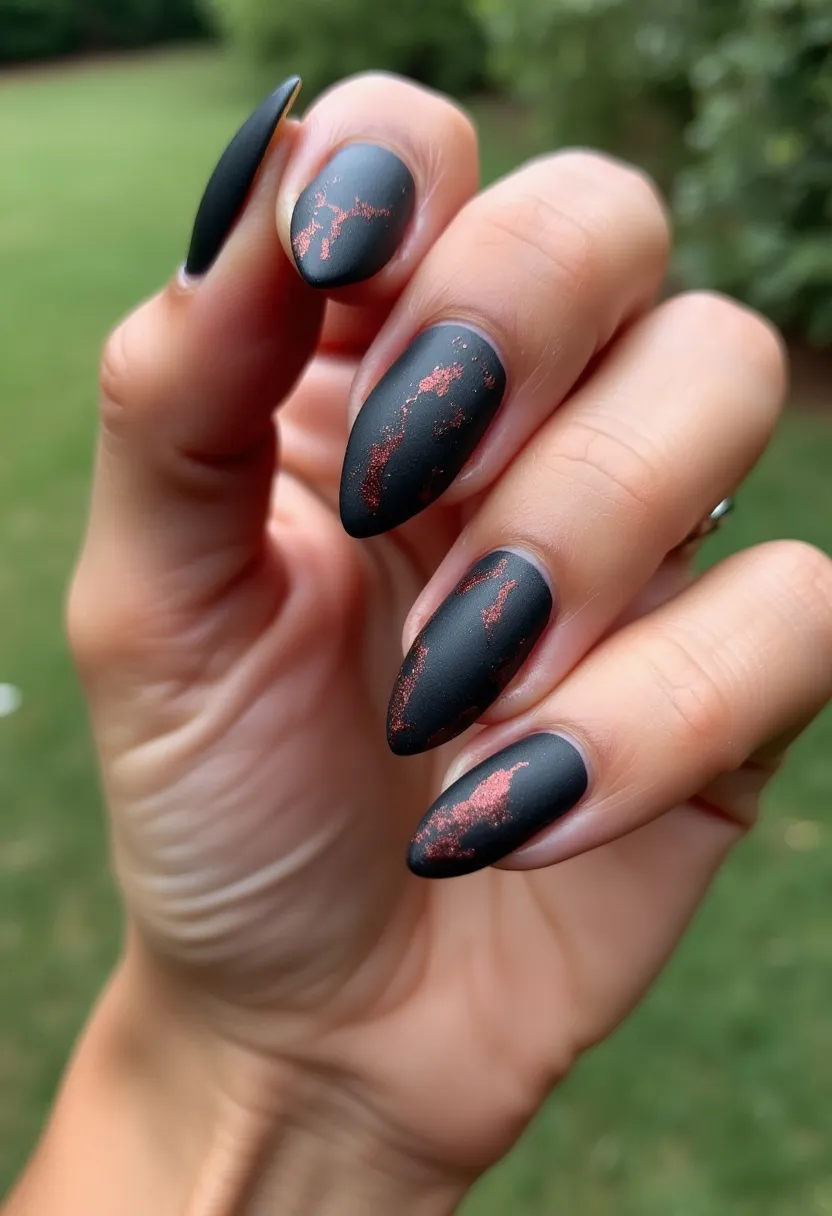 The nail design features a striking matte black base color, making use of the gel nail treatment for a smooth, long-lasting finish. The nails are almond-shaped, providing an elegant and elongating effect to the fingers. Intricate patterns of copper or rose gold foil are dispersed sporadically across the nails, adding a touch of metallic shimmer that contrasts beautifully with the matte background. These foil accents create a marbled or cracked texture effect, giving the design a unique and sophisticated appearance. This nail art could be ideal for the autumn season with its dark, moody color palette mixed with warm metallic details, making it perfect for special occasions or festive events during this time of year.