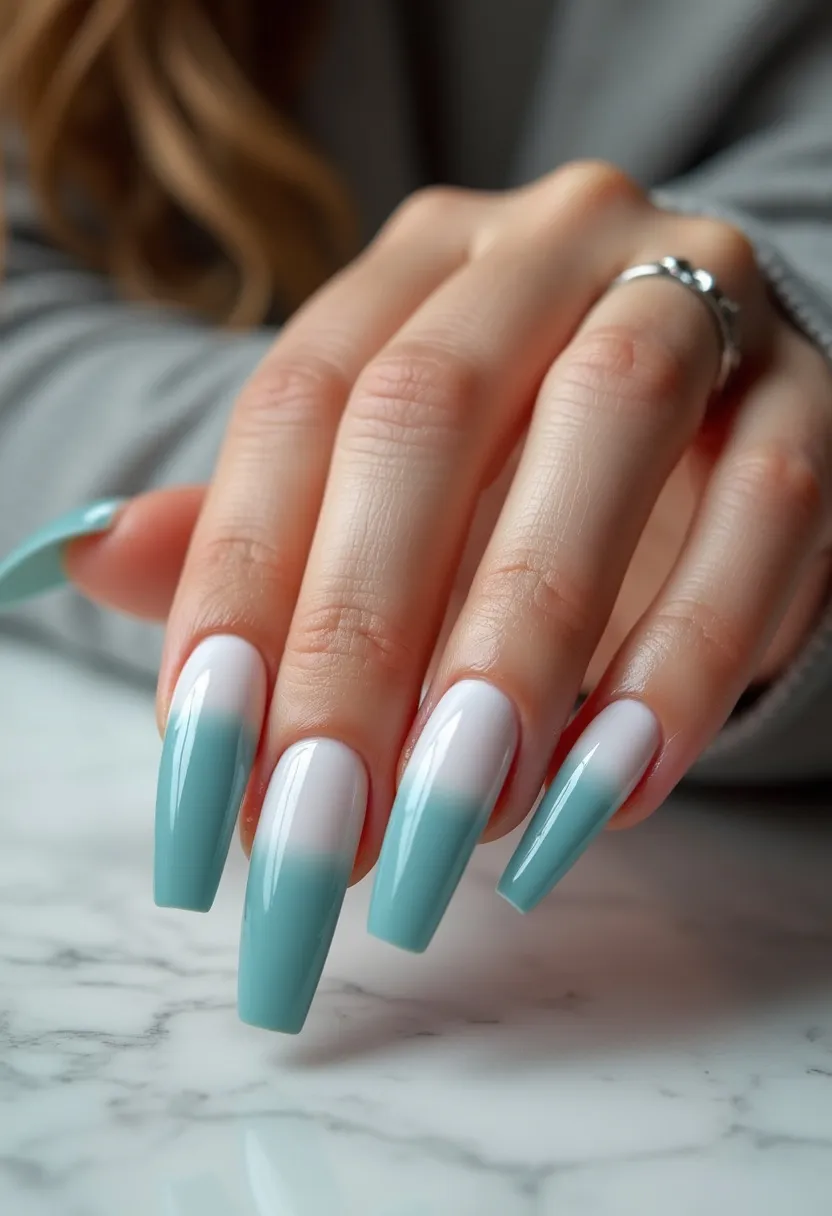 The nail design features a soft and elegant color palette transitioning from white at the base to a serene seafoam green towards the tips, creating a gradient or ombré effect. The nails are long and shaped into a tapered square, commonly known as coffin shape. This design appears to use a gel treatment, given the high-gloss finish and smooth gradient blending. The nails have a polished and uniform look, with no additional patterns or decorations. The soft color transition evokes a tranquil, almost beach-like or seasonal spring vibe, making it suitable for occasions that call for a subtle yet sophisticated aesthetic.