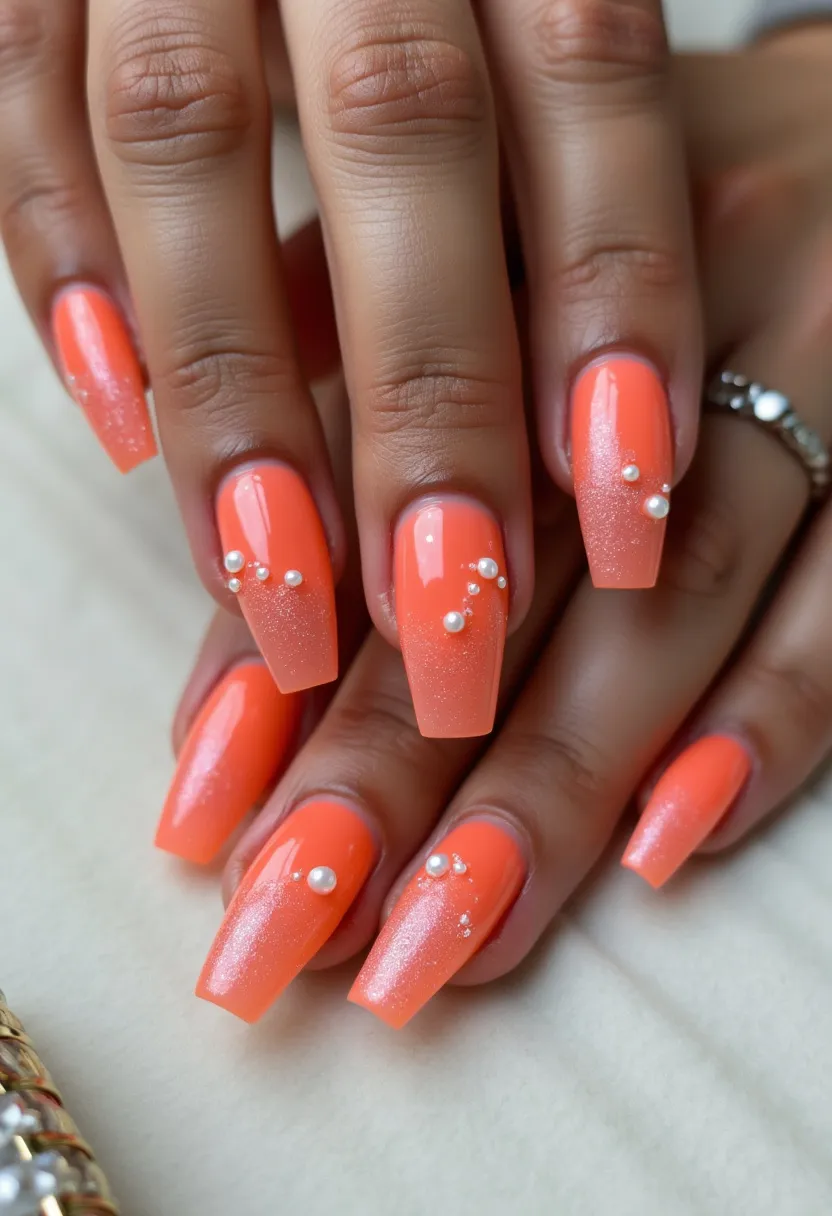 This nail design showcases a vibrant, summery orange palette, with the nails shaped in a chic, coffin or ballerina style. The nails appear to be created with a gel treatment, providing a smooth and glossy finish. The design features a delicate gradient effect transitioning to a slightly glittery tip, adding a festive sparkle. Intricate decorations include small pearl accents arranged in a tasteful pattern near the cuticles, enhancing the overall elegance of the look. This design is suitable for summer outings and festive occasions, offering a blend of bold color and subtle, luxurious details.