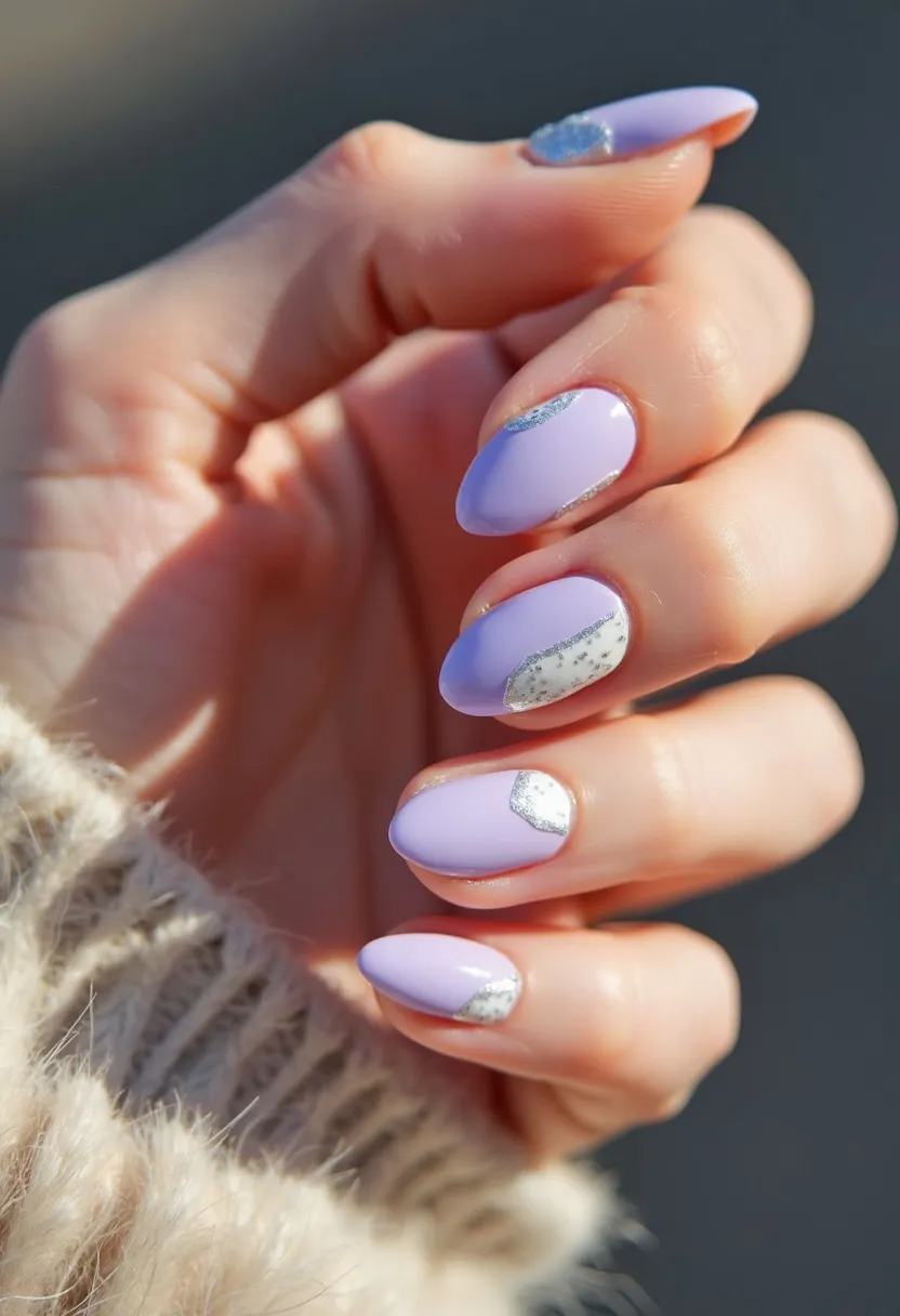 The nail design features an almond shape with a polished, glossy finish, possibly achieved with gel treatment. The primary color is a pastel lavender, giving a soft and elegant appearance. Each nail has unique silver foil accents, creating a chic and modern look with a touch of sparkle. The combination of the light lavender and silver elements makes this design suitable for the spring season or special occasions like weddings or celebrations, where a delicate and sophisticated style is desired. The silver accents vary in size and placement, adding a playful yet refined detail to the overall design.