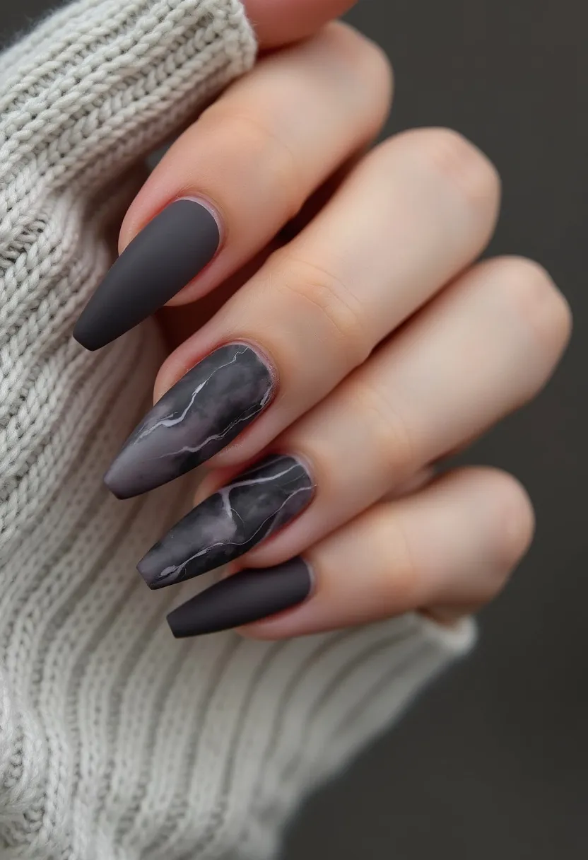 This nail design features a dark color palette, primarily using shades of matte black and gray. The nails are shaped in a long, tapered coffin or ballerina style, creating an elegant and dramatic silhouette. Two of the nails showcase an intricate marbled pattern, mimicking the natural veining found in stone, adding texture and visual interest to the overall look. The marbled design has subtle white streaks against the dark background, enhancing the sophisticated aesthetic. The nails appear to have a matte finish, suggesting the use of matte gel polish for a velvety texture. This design is versatile and can be suitable for various seasons, particularly autumn or winter, and would be fitting for special occasions or a stylish everyday look.