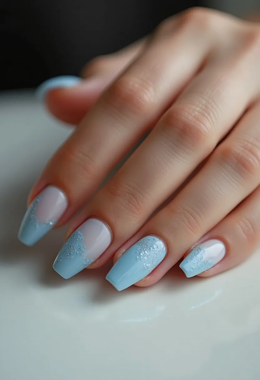 The nail design features a soothing color palette of light blue and soft pinkish-white hues. The nails are in a coffin or ballerina shape, offering a modern and elegant look. Intricate patterns resembling delicate lace or snowflakes are meticulously crafted in a shimmery silver glitter on the light blue sections, adding a touch of sparkle and sophistication. The manicure appears to be crafted with gel polish, ensuring a glossy and long-lasting finish. The design's cool tones and glitter make it an ideal choice for winter or festive occasions, evoking a sense of frosty elegance and seasonal charm.