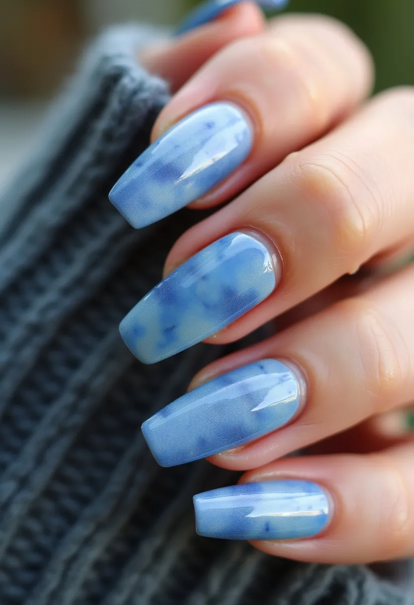 This nail design features square-shaped nails with a soft and elegant palette of light blue and white, creating a marble-like effect. The colors blend seamlessly together, giving a cool and sophisticated appearance. The nails appear to have been treated with gel polish, providing a high-gloss finish and durable look. The intricate marble pattern is achieved through a combination of lighter blue swirls and subtle hints of white, adding depth and texture to the design. This design could be perfect for winter or any special occasion that calls for a refined and chic look.