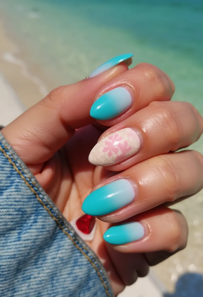 The nail design features almond-shaped nails with a soothing turquoise and white color palette, creating a gradient or ombré effect that suggests a tranquil beach or ocean theme. The ring finger stands out with a delicate pink floral pattern set against a softly textured white background, adding an elegant touch to the overall look. The nails are likely treated with gel polish, given the glossy finish and smooth application apparent in the design. The bright and fresh colors, coupled with floral detailing, suggest a spring or summer theme, making them ideal for a vacation or casual outdoor event.