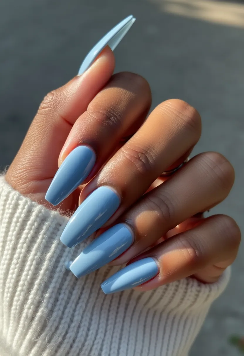 The nail design features a stunning light blue color palette, which gives off a fresh, calm appearance. The nails are shaped in a long, tapered square style, often referred to as coffin-shaped. The nail color is applied evenly with a high-gloss finish, suggesting that a gel or shellac treatment might have been used to achieve the smooth and shiny look. This design is simple yet elegant, devoid of intricate patterns or decorations, allowing the color and shape to stand out. The soft blue tone gives a hint of seasonal winter or spring vibes, making it suitable for various occasions ranging from casual outings to more formal events.