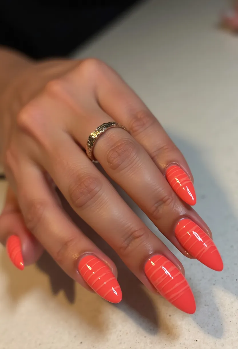 The nail design features a vibrant, coral-orange color palette that radiates warmth and energy. The nails are fashioned in a stiletto shape, characterized by their sharp, pointed tips. Each nail is adorned with fine, white linear patterns, adding an element of intricate artistry and sophistication. The high-shine finish and the durability of the coating suggest that the nails are treated with gel, providing a glossy and polished appearance. The vibrant hue combined with the linear detailing makes these nails perfect for a summer aesthetic or a festive occasion, embracing a playful yet chic vibe.