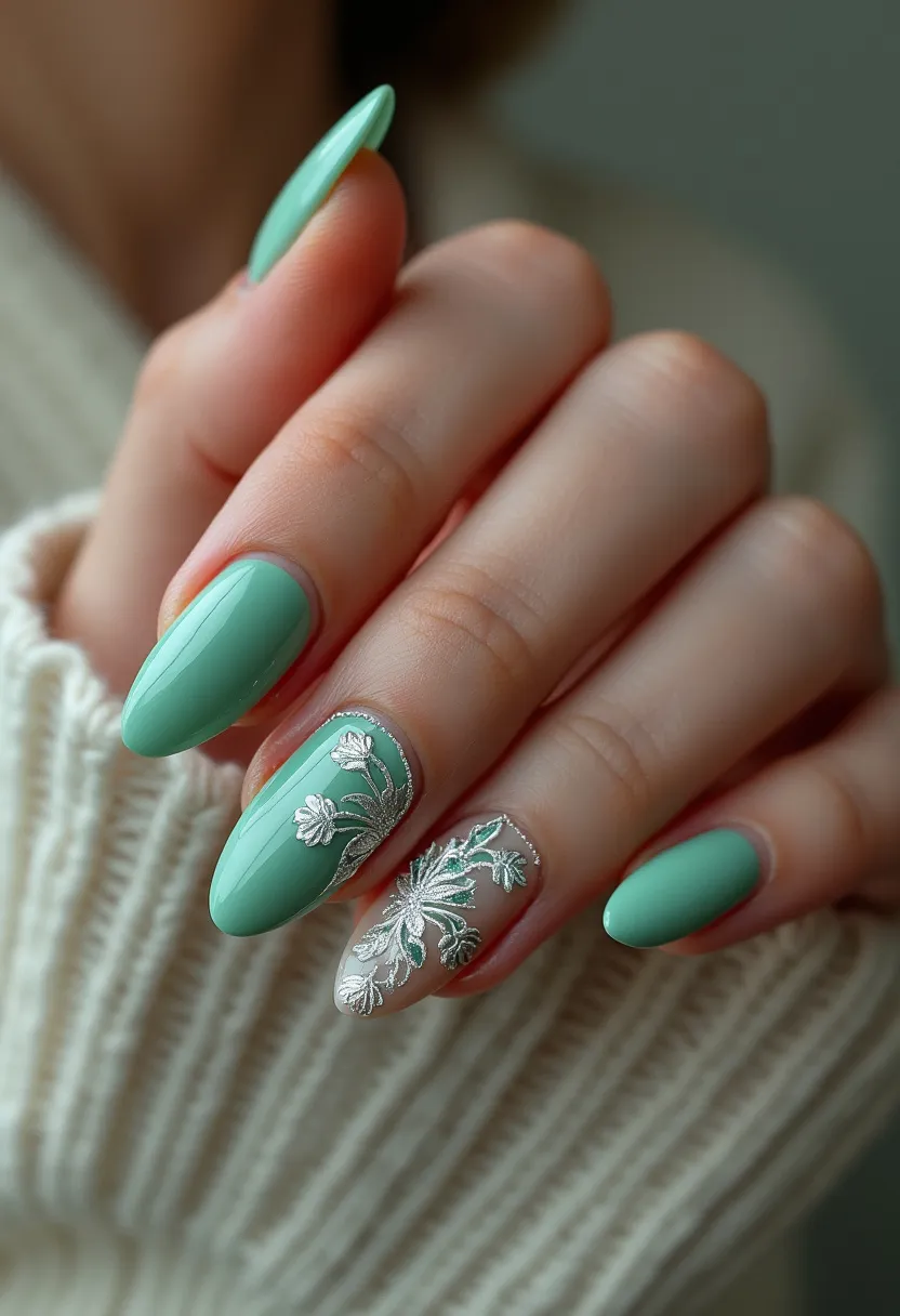 This nail design features an elegant and fresh look, primarily using a pastel green color palette. The nails are shaped in a medium-length almond style, accentuating the fingertips with a sophisticated curve. The treatment appears to be a gel manicure due to the high-gloss finish and smooth application. Unique details include intricate silver floral patterns, which are delicately placed on the ring finger and middle finger. The ring finger has a clear base with detailed white and silver floral designs, adding an element of contrast and intricacy to the overall look. This design is suitable for a spring or summer theme, evoking a sense of freshness and natural beauty.