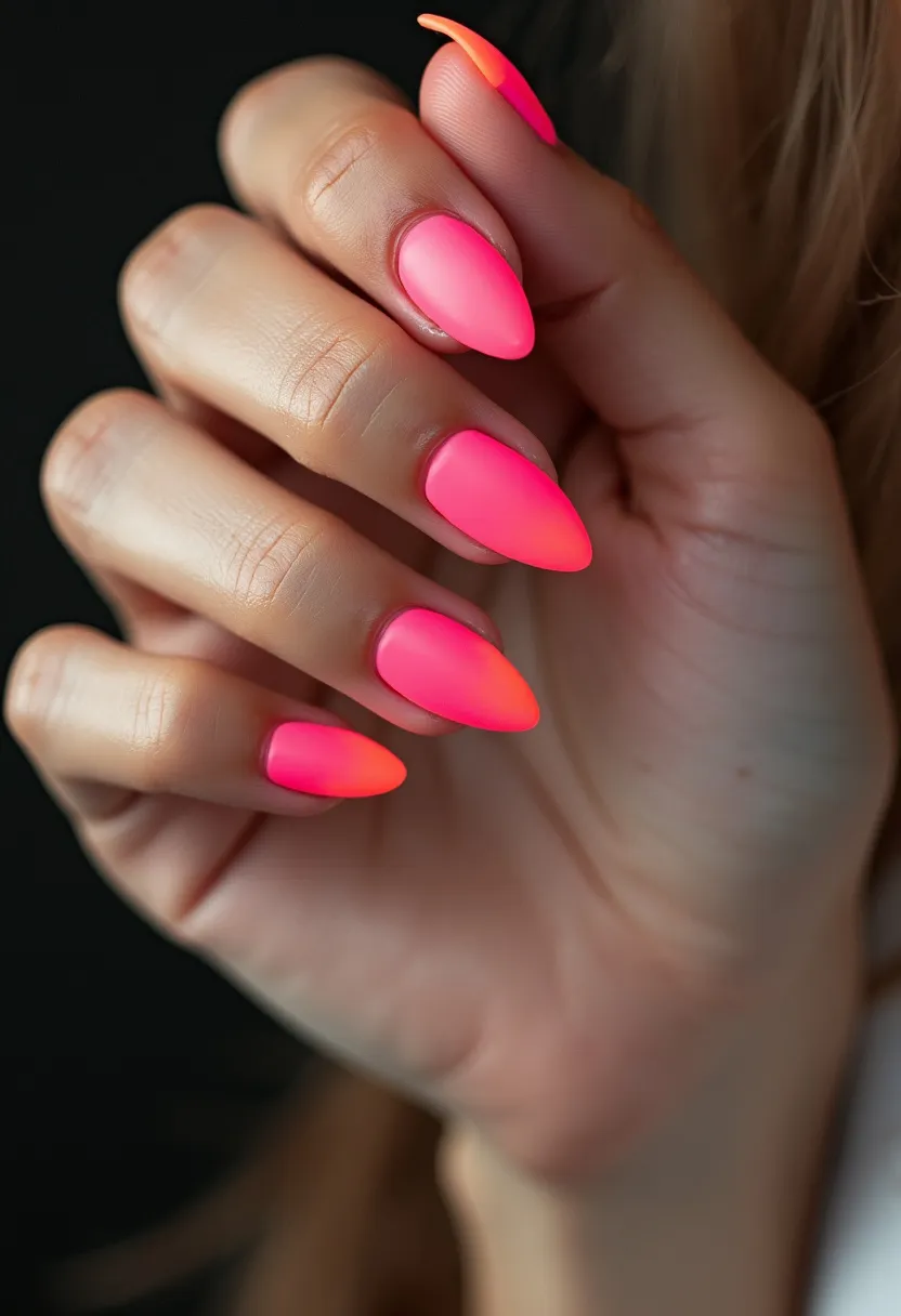 The nail design features a striking neon color palette with vibrant shades of pink and orange, creating an eye-catching gradient effect. The nails are shaped into a sharp almond style, elongating the fingers and adding a chic and edgy vibe to the overall look. These nails appear to have a matte finish, which adds a sophisticated touch to the bright, bold colors. The treatment seems to be a gel manicure, providing a smooth and durable finish that ensures the vivid shades remain intact for an extended period. This design is perfect for the summer season, capturing the essence of sunny days and vibrant nightlife, while also being suitable for special occasions that call for a standout nail aesthetic.