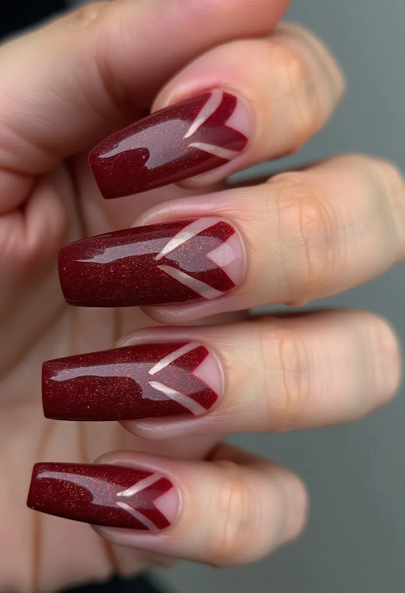 The nail design features a sophisticated color palette with a dominant deep red shade that has a subtle shimmer, giving the nails a lustrous finish. The nails are squared off at the tips, providing a modern and stylish look. There is a clear base near the cuticles with abstract diagonal lines extending into the red shimmer part, creating a geometric pattern that adds a touch of elegance. The precise lines and glossy finish suggest that a gel or shellac treatment has been used to achieve this design. This intricate nail art could be well-suited for the winter season or special occasions like holidays or festive gatherings, offering a unique and sophisticated appearance.