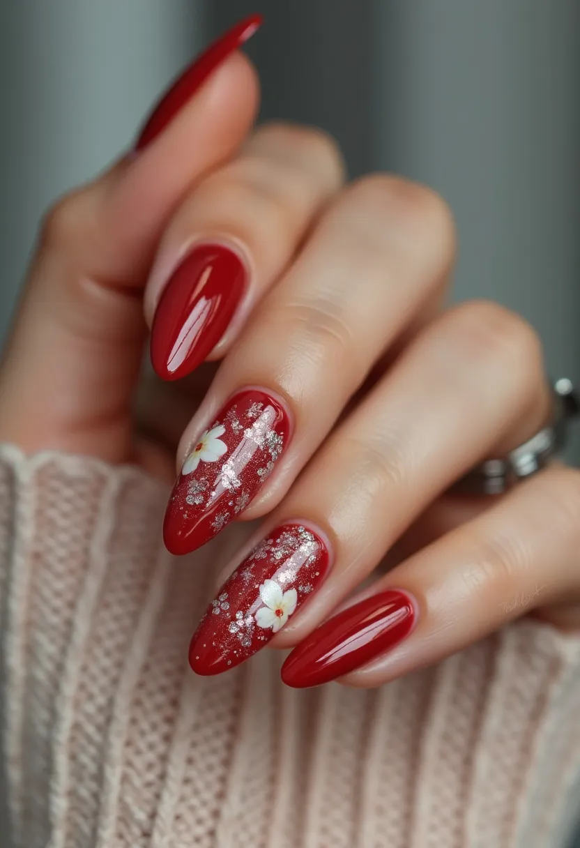 The nail design showcases a rich, deep red color palette, adding a touch of elegance and sophistication. The nails are long and almond-shaped, accentuating the sleek and feminine aesthetic. Some nails feature intricate patterns including delicate white floral details and subtle glitter accents on a couple of nails, adding a sparkling effect. The glossy finish suggests a gel or shellac treatment, enhancing durability and shine. The design has a versatile appeal, suitable for various seasons, potentially aligning with festive celebrations or romantic occasions such as Valentine's Day or weddings. The overall look combines classic and contemporary elements, making it both timeless and chic.