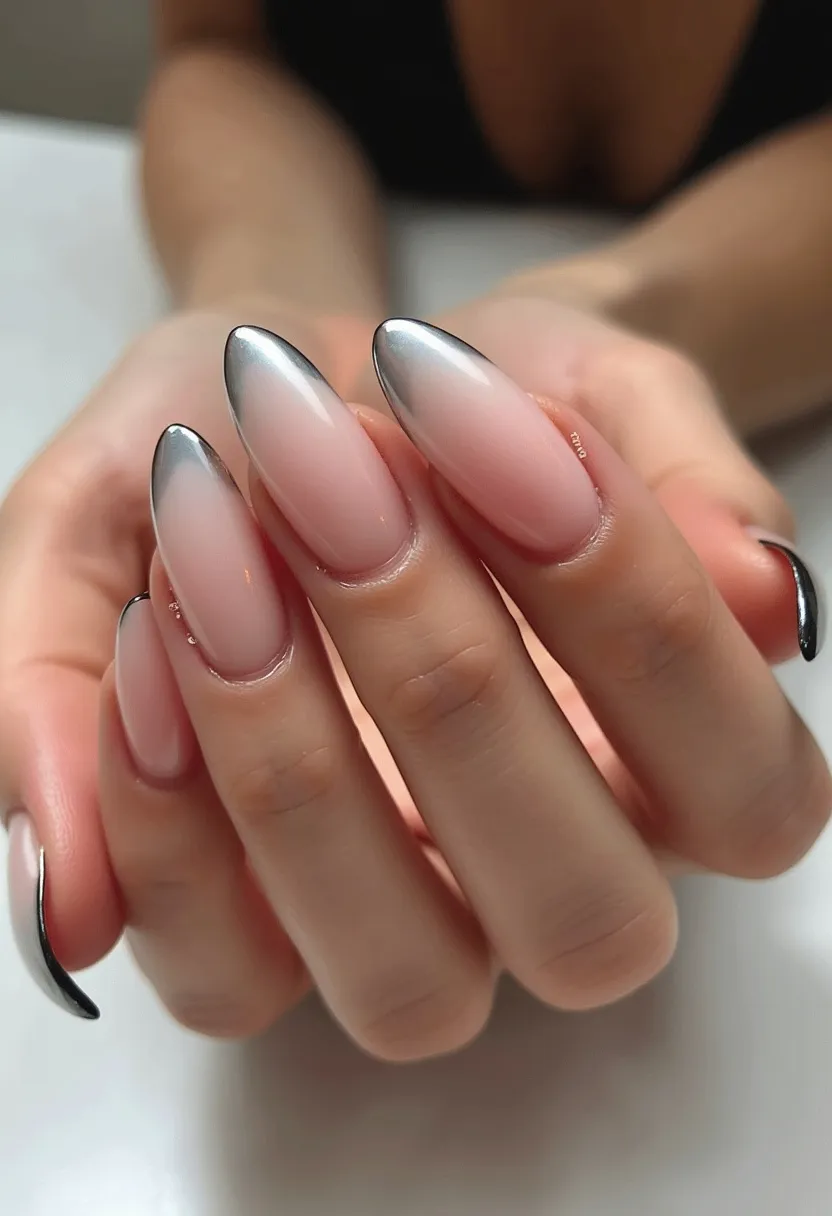 The nail design showcases almond-shaped nails treated with what appears to be a gel or acrylic finish, providing a smooth and glossy surface. The color palette features a gradient ombre effect, transitioning from a soft, natural pink at the base to a metallic silver at the tips. This elegant gradient is accentuated by a chrome-like effect on the tips, giving the nails a polished and futuristic appearance. The sophisticated design with its subtle yet striking color transition suggests versatility for various occasions, including formal events or the holiday season. The overall look is modern and chic, with a refined and professional execution.