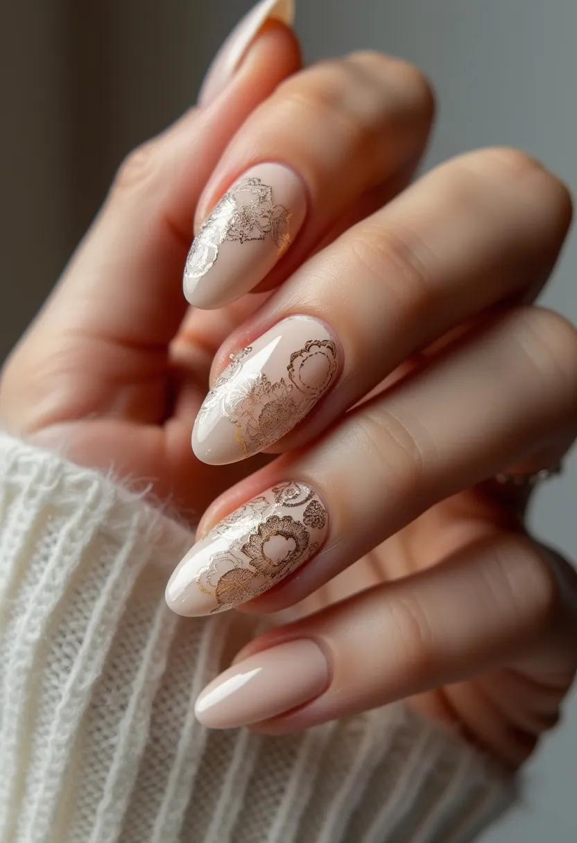 The nail design showcases a refined, stylish aesthetic with a soft nude color palette. The nails are almond-shaped, giving them an elegant and elongating appearance. This manicure features intricate floral lace patterns in a delicate gold hue, adding a touch of sophistication and intricacy to the design. The finish appears to be a gel treatment, providing a glossy and durable sheen. The golden lace details over the nude base could suggest a seasonal theme like autumn or a special occasion such as a wedding or formal event, offering a harmonious balance between simplicity and opulence.