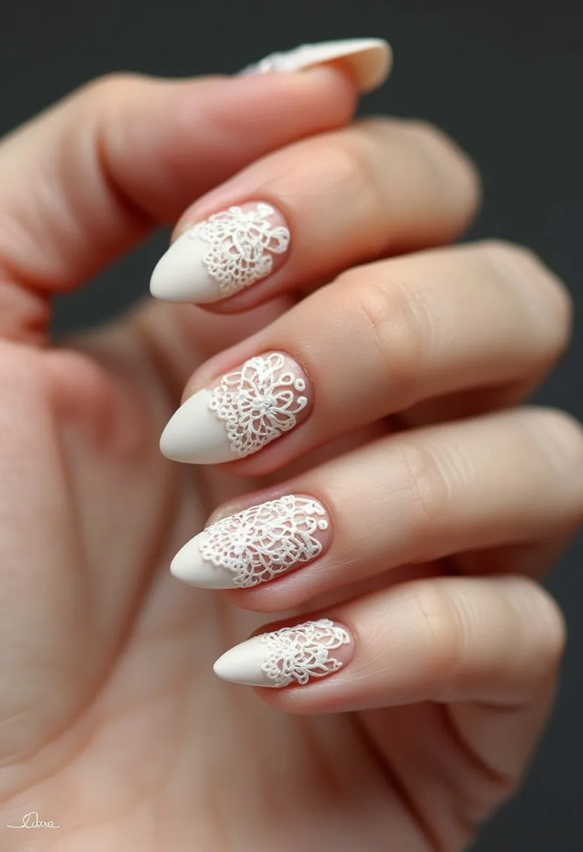 The nail design features a sophisticated and elegant look with a primarily white color palette. The nails are almond-shaped, offering a classic and elongated appearance. Each nail is adorned with intricate lace-like patterns at the tips, creating a delicate and feminine touch. The transition between the natural nail bed and the white tips displays a fine detailing that indicates a professional nail treatment, most likely gel due to its smooth finish and durability. This design might be ideal for a bridal or special occasion, given its elegant and refined aesthetic. The intricate lace patterns add a touch of sophistication and charm, perfect for celebrating a memorable event.