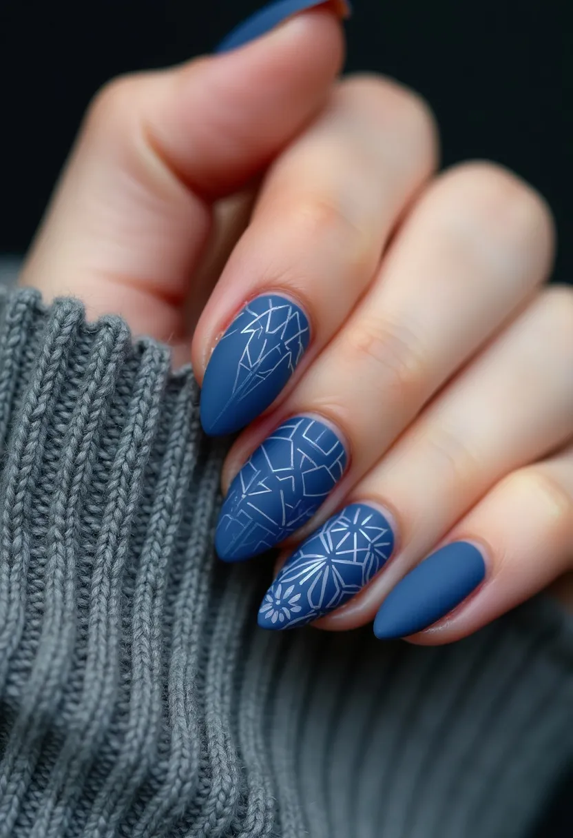 The nail design features a sophisticated winter-themed look with a predominant matte blue color palette, enhanced by intricate white geometric and snowflake-like patterns on accent nails. The nails are shaped in an elegant almond style, providing a balanced and chic appearance. The delicate white designs contrast beautifully against the matte blue backdrop, adding a touch of festivity appropriate for the winter season or holiday occasions. The use of gel polish is evident from the smooth and glossy finish, ensuring durability and a lasting vibrant look. Overall, this nail design combines simplicity with detailed artistry, offering a modern and stylish take on winter nail art.