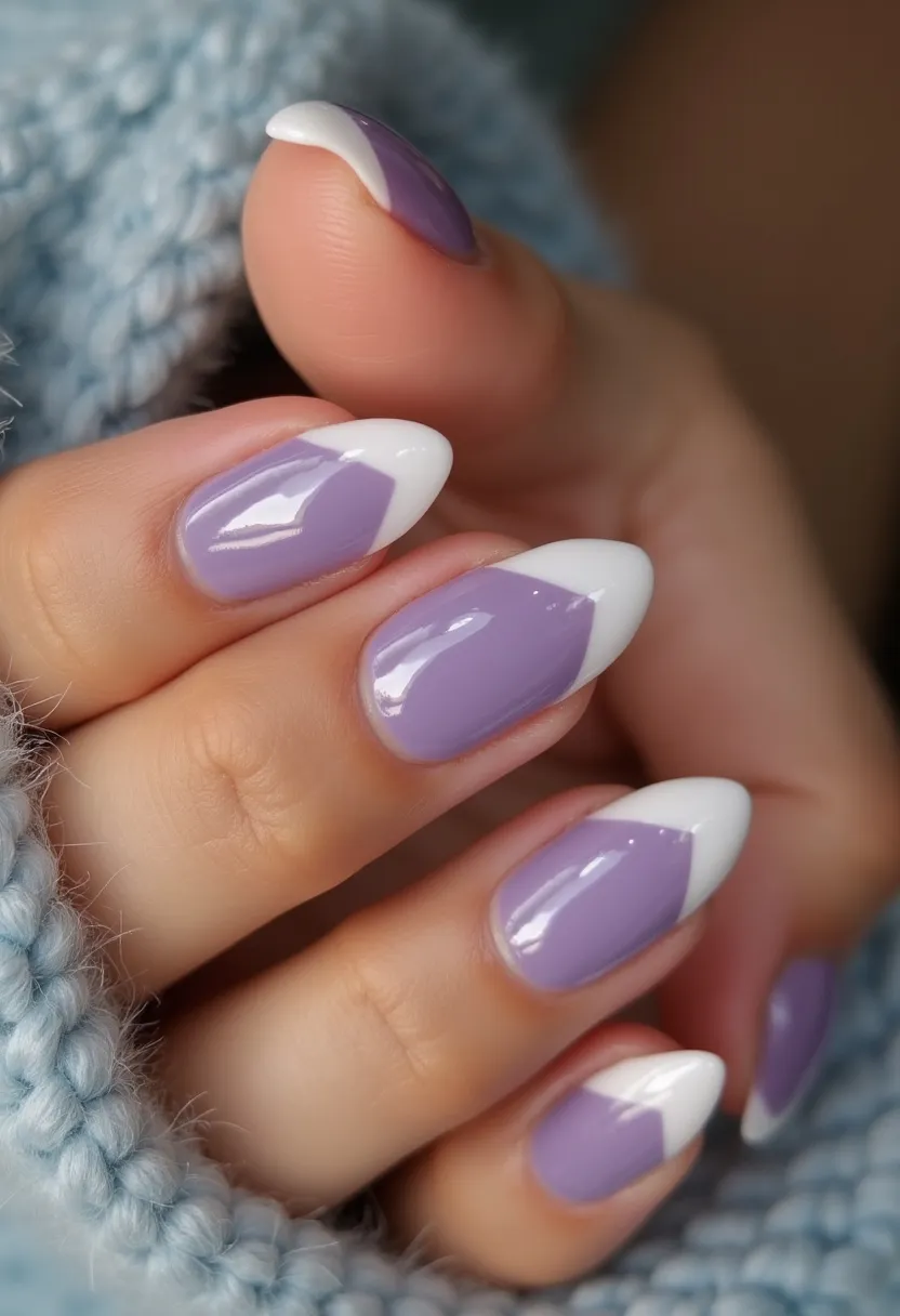 The nail design features a sophisticated and modern look with an almond nail shape. The color palette primarily includes a soft lavender base complemented by crisp white tips in a stylish twist on the classic French manicure. The nails exhibit a glossy finish that suggests a gel or possibly shellac treatment, offering durability and high shine. The intricate pattern is characterized by a diagonal split where the lavender base beautifully contrasts with the white tips, creating a chic and elegant appearance. This nail design is versatile, suitable for various occasions, and adds a touch of refinement, making it an excellent choice for both everyday wear and special events.