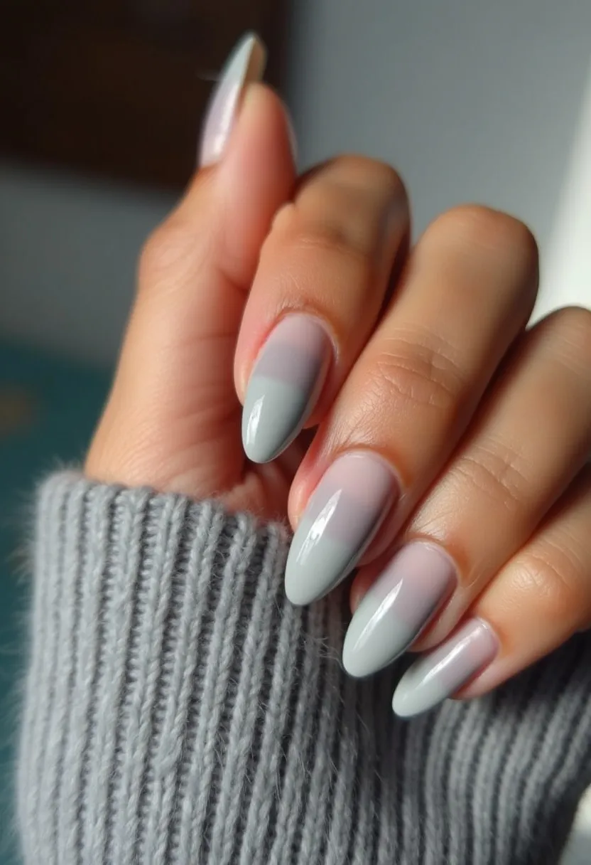 The nail design features a sophisticated and elegant look, with a color palette that transitions from a soft, muted lavender at the base to a subtle, light gray towards the tips, creating a smooth gradient effect. The nails are almond-shaped, providing a sleek and refined appearance. The treatment appears to be gel-based, given the high-gloss finish and smooth surface. This design does not seem to specifically cater to any seasonal themes or special occasions, but the choice of muted, understated hues and the gradient technique lend itself well to a versatile and sophisticated look suitable for various occasions.