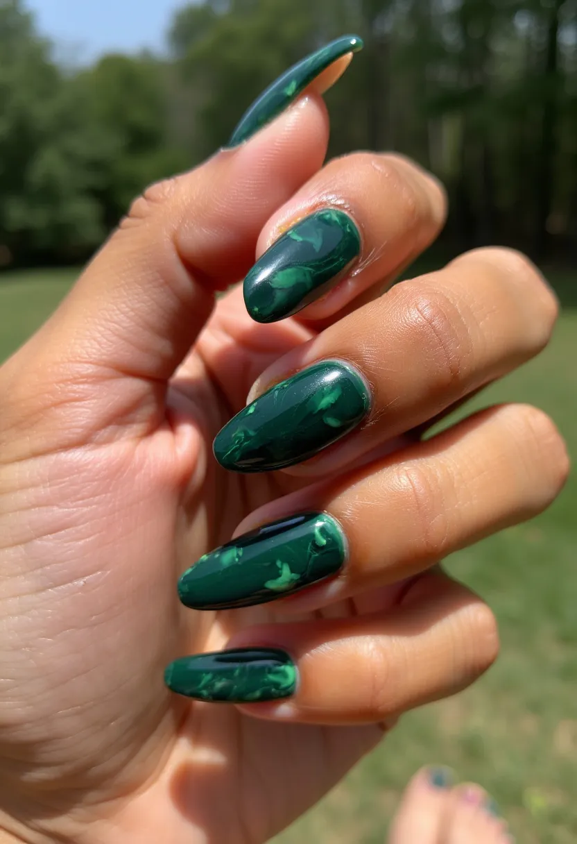 The nail design showcases an elegant palette of deep forest green with lighter green marbling. The nails are shaped in a sophisticated and stylish almond form, adding length and a subtle point to the ends. The intricate marbled pattern provides a natural and organic aesthetic, with swirls of lighter green running through the darker base, creating depth and visual interest. This design appears to have been created using a gel treatment, evident from its high shine and smooth finish. The rich green tones make it a versatile choice, suitable for both seasonal themes like autumn or winter and special occasions where a touch of nature-inspired elegance is desired.