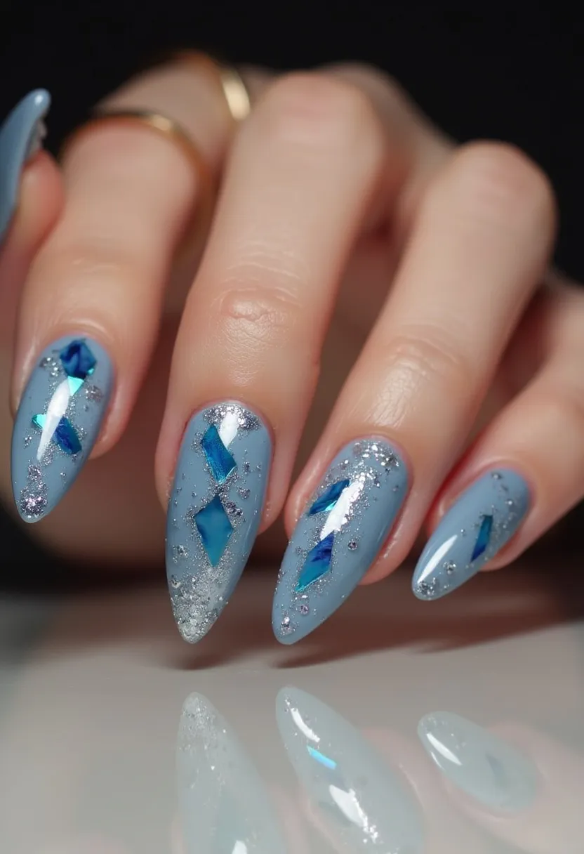 The nail design features a sophisticated color palette of cool tones, highlighted predominantly by a soft blue base. The nails are shaped into long, pointed almonds, creating a sleek and elegant look. Intricate patterns adorn each nail, showcasing a combination of glitter and holographic diamond-shaped decorations in vivid blue shades, adding both depth and dimension. The sparkling accents, likely applied using a gel treatment, lend a reflective, almost icy quality to the nails. This design evokes a winter theme, making it particularly suitable for festive occasions or the holiday season.