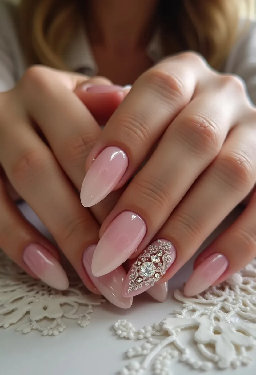 The nail design features a sophisticated and elegant look, highlighted by a soft pink and white color palette that creates a gradient or ombre effect. The nails are almond-shaped, providing a refined and elongated appearance. The intricate nail art on the accent nail is particularly striking, adorned with shimmering rhinestones and delicate metallic embellishments arranged in a decorative pattern, adding a touch of glamour and luxury. The use of what appears to be gel nail treatment ensures a glossy and durable finish. This design is perfect for special occasions such as weddings or formal events, as it combines elegance and subtlety with a hint of sparkle.