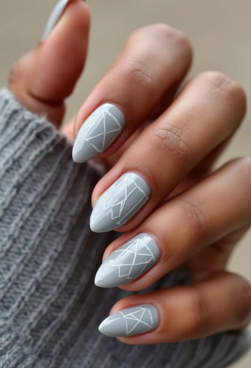 This nail design features a calming grey color palette combined with geometric white line patterns, offering a modern and minimalist aesthetic. The nails are shaped in a stylish almond form that gives a sleek and elongated appearance to the fingers. These nails appear to be treated with gel polish, providing a durable and glossy finish. The intricate white geometric designs add a unique flair, making the nails stand out without being overly extravagant. This design is suitable for the winter season or casual occasions, where subtle yet chic nail art is desired.