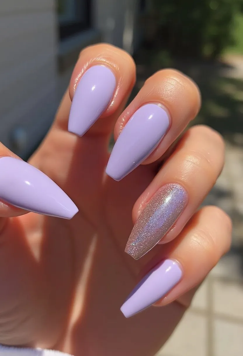 The nail design features a lovely pastel lavender color palette, creating a soft and elegant look. The nails are shaped in a long, almond style, providing a chic and sophisticated appearance. Among the five nails, one accent nail stands out with a glittery, metallic silver shade, adding a touch of glamour and contrast to the overall design. The shimmer effect on this nail enhances the luxurious feel of the design. The treatment used appears to be a gel manicure, ensuring a glossy finish and long-lasting wear. The combination of pastel and metallic elements gives a versatile yet stylish look suitable for seasonal transitions like spring or special occasions like weddings and parties.