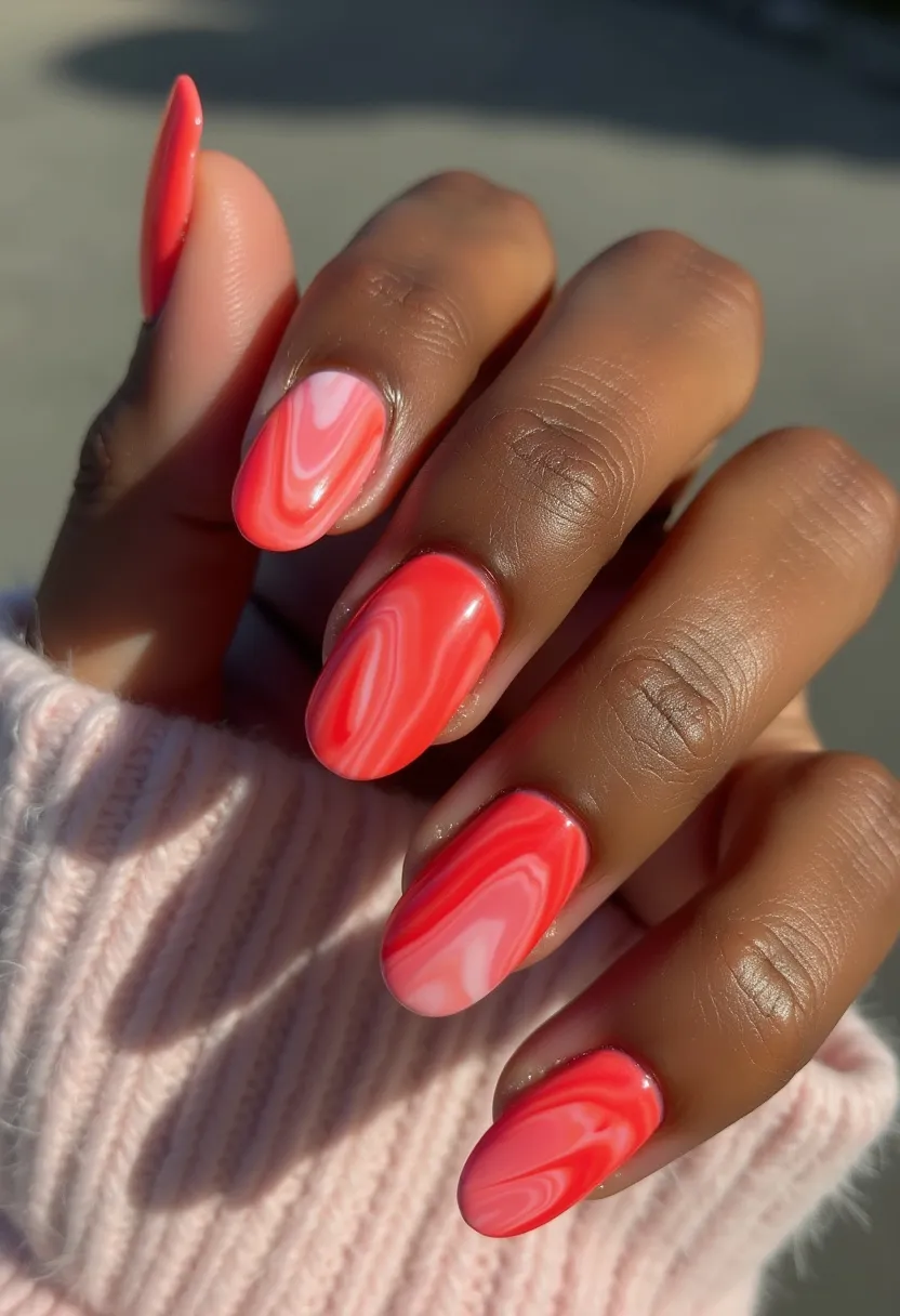 This nail design features a vibrant and eye-catching color palette primarily composed of various shades of pink and red. The nails are medium-length with a classic oval shape, providing a sleek and elegant appearance. The design includes an intricate marbled pattern that seamlessly blends the shades together, creating a smooth, fluid effect across each nail. The consistent gloss and shine suggest the use of gel treatment, enhancing the durability and finish of the manicure. The bright, warm hues and dynamic design give the nails a summery or festive feel, perfect for special occasions or simply to add a pop of color.