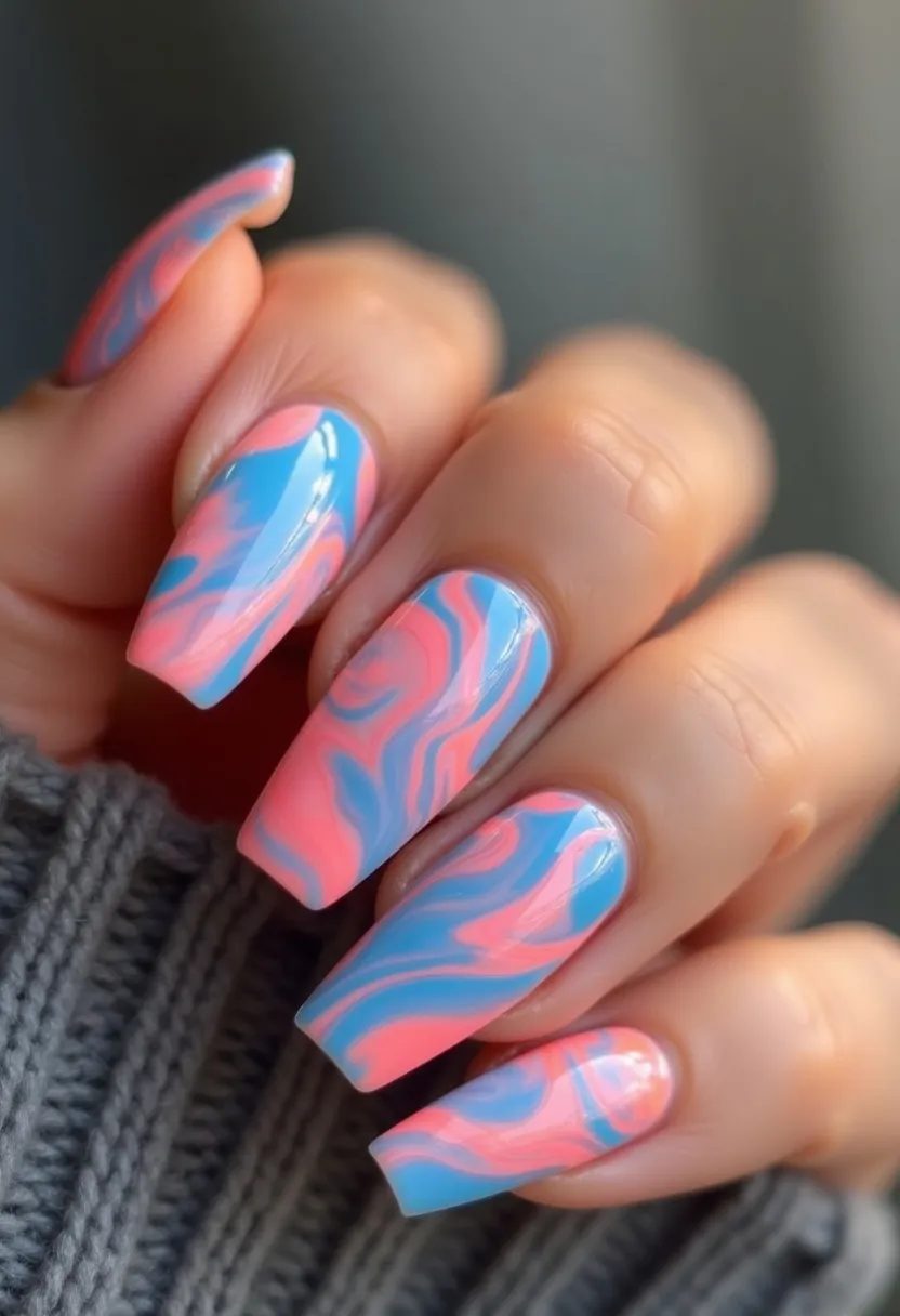 The nail design features a vibrant and eye-catching color palette of predominantly blue and pink hues, creating a swirling marbled effect. The nails are shaped in a stylish, long coffin style, which adds to their glamorous and trendy appearance. The intricate marbled pattern seamlessly blends the colors together, giving each nail a unique yet cohesive look. This design is likely achieved using a gel nail treatment, as indicated by the high-gloss finish and smooth texture. The overall aesthetic gives a fun, playful, and possibly summer or springtime vibe, suitable for someone looking to make a bold fashion statement with their nails.