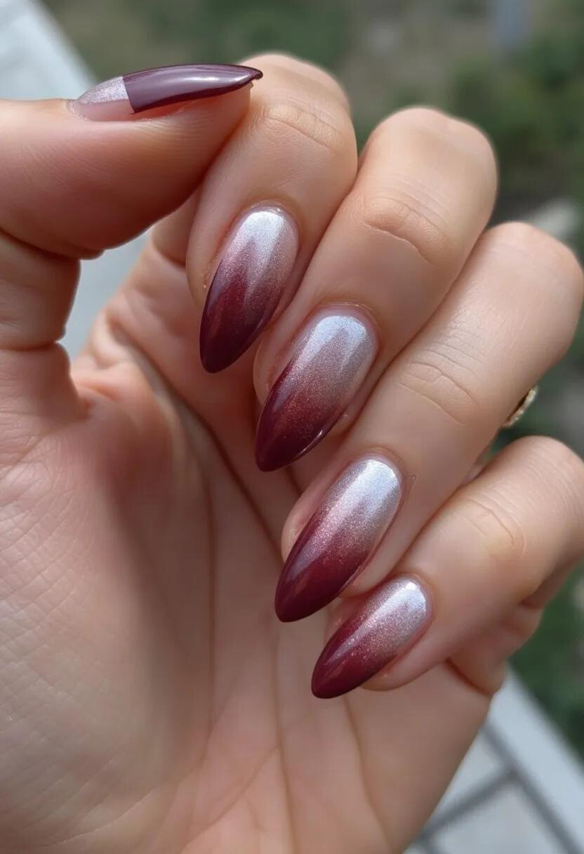 This nail design features a gorgeous color palette of deep burgundy and a metallic silver that blends seamlessly together. The nails are shaped into elegant almond tips, a popular and sophisticated shape that elongates the fingers. The intricate pattern is an ombre effect, starting with the metallic silver at the base and transitioning smoothly into the rich burgundy at the tips. The glossy finish suggests that these nails are most likely treated with gel or shellac, both of which provide a long-lasting and lustrous shine. The combination of colors and the luxurious sheen indicates that this nail design could be well-suited for the fall season or special occasions, adding a touch of glamour and refinement to the overall look.