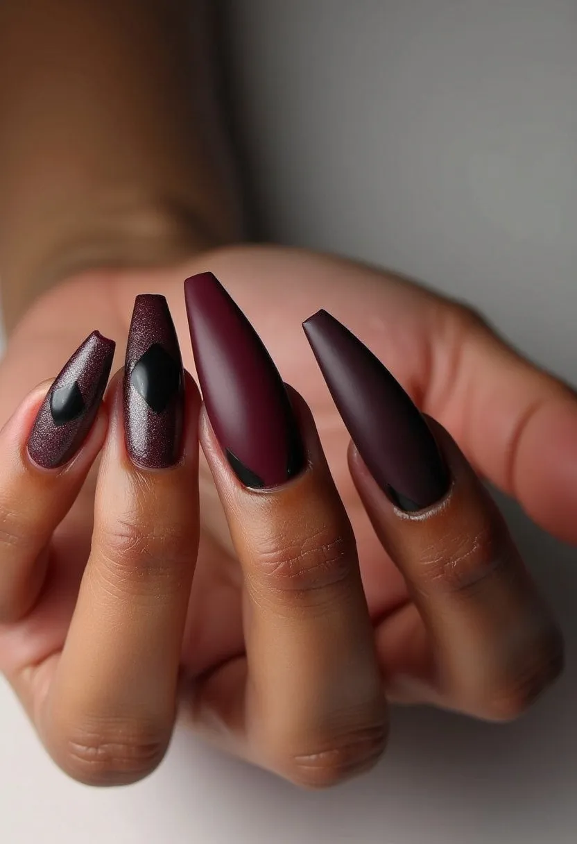 The nail design features a deep, rich palette dominated by burgundy and black hues, creating a sophisticated and striking look. The nails are shaped in a long, tapered almond form, enhancing the elegance of the design. Intricate black diamond patterns accentuate the two middle fingers, adding a subtle yet intricate detail to the overall aesthetic. The finish appears to be matte, likely achieved with gel treatment, ensuring a smooth and polished appearance. This design is perfect for a formal event or the autumn/winter seasons, offering a chic and contemporary flair with its dark, velvety tones.