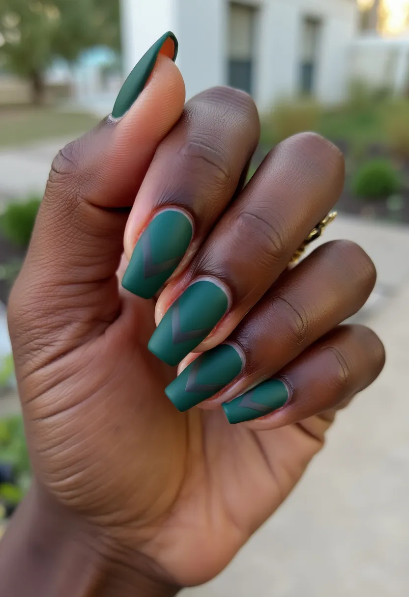 This nail design features a rich, matte forest green color palette, perfect for an autumn or winter seasonal theme. The nails are long with a coffin shape, providing a modern and sleek look. A distinctive feature of this design is the minimalist and clean-lined chevron pattern on each nail, created with a darker green hue to offer subtle contrast without overpowering the overall aesthetic. The nails appear to be treated with a matte finish, likely achieved through gel polish to ensure durability and longevity. The elegant combination of colors and geometric designs adds a sophisticated touch suitable for both everyday wear and special occasions.