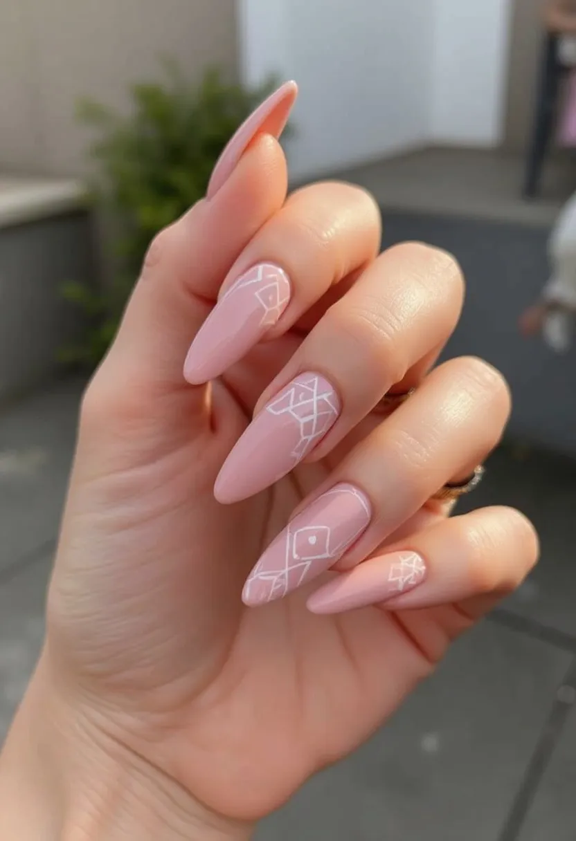 This nail design features a soft, dusky pink color palette, applied via a gel nail treatment for a glossy, long-lasting finish. The nails are shaped in a sharp almond style, providing an elegant and modern look. Intricate white geometric patterns adorn a few select nails, adding a sophisticated contrast to the solid pink base. The design includes rhombus shapes and intersecting lines, giving it a delicate, abstract feel. This nail art could be suitable for a variety of occasions, both casual and formal, and hints at a contemporary and refined style, possibly appealing for spring or summer seasons due to its light color and airy design.