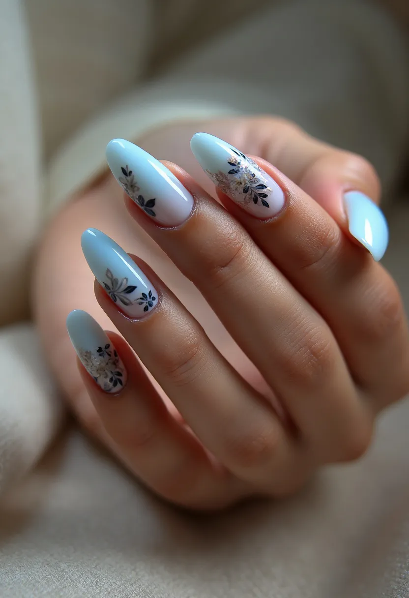 The nail design features a soft pastel blue color palette with almond-shaped nails. Each nail is adorned with intricate floral patterns in shades of black and white, giving a delicate and elegant look. The floral designs are meticulously placed, with some nails showcasing more detailed blossoms while others have simpler, smaller flowers. The type of nail treatment appears to be gel, lending a glossy finish that enhances the overall appearance. This design is versatile, suitable for both everyday wear and special occasions, and its subtle yet sophisticated details make it an appealing choice for the spring or summer seasons.