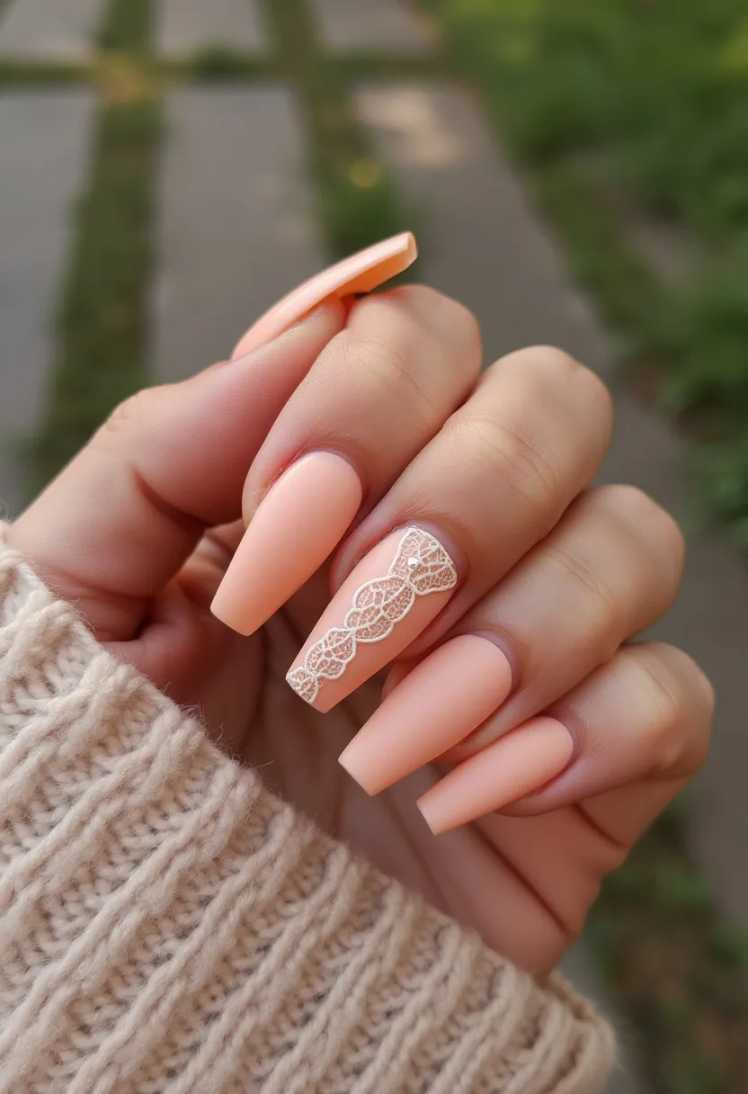 The nail design showcases a feminine and elegant style with long, almond-shaped nails coated in a soft, matte peach color. This set involves an intricate lace pattern accentuated on the ring fingernail, enhancing the overall design with a touch of sophistication and delicacy. The lace detail features white geometric and floral motifs running vertically along the nail, likely applied using nail stamping or decals. This particular design could be achieved using gel polish, providing a sturdy base and a smooth, elegant finish. The subtle peach palette and lace accents evoke a spring or summer theme, making it suitable for weddings, bridal showers, or any romantic occasion.