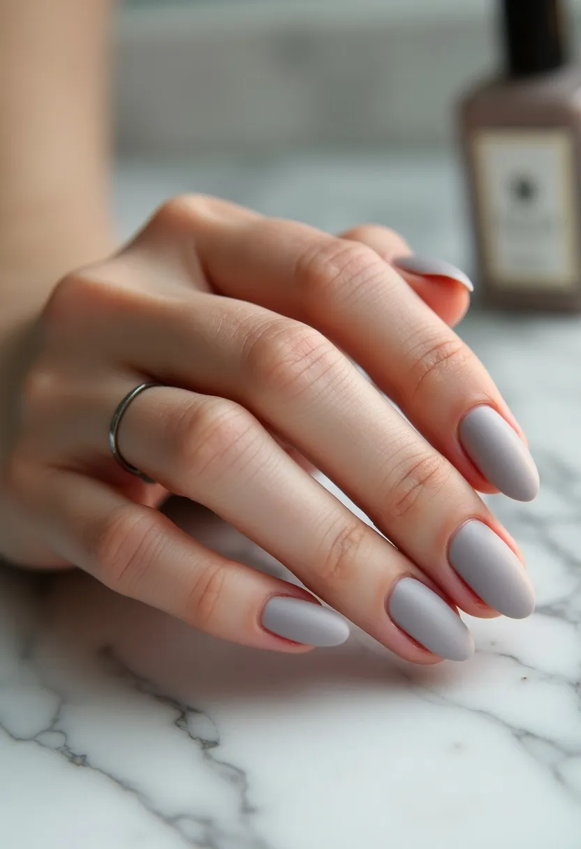 The nail design features a sleek and sophisticated matte finish in a cool-toned, light grey color, creating a minimalist and modern look. The nails are shaped into an almond form, which provides a feminine and elegant silhouette. This nail design does not showcase any additional intricate patterns or decorations, allowing the matte grey color to take center stage. The nail treatment appears to be gel due to the smooth and seamless finish that gel polishes are known for. This style is versatile and suitable for any season, offering a timeless and understated elegance that can be worn for both casual and formal occasions.