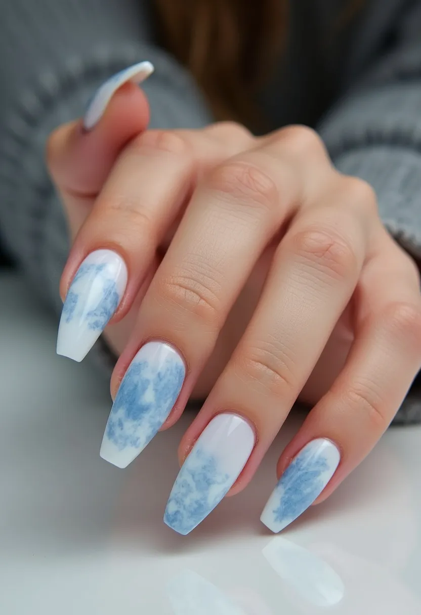 The nail design features a sophisticated and elegant marble effect realized through a muted color palette of white and soft blue. The nails are shaped in a long, coffin style, providing a sleek and modern appearance. Each nail is adorned with a marbled pattern blending white and various shades of blue, creating an artistic and bespoke look. The treatment appears to be done using gel polish to achieve a glossy, smooth finish that enhances the intricate design. This design could be ideal for winter months or special occasions, offering a refined and stylish statement.