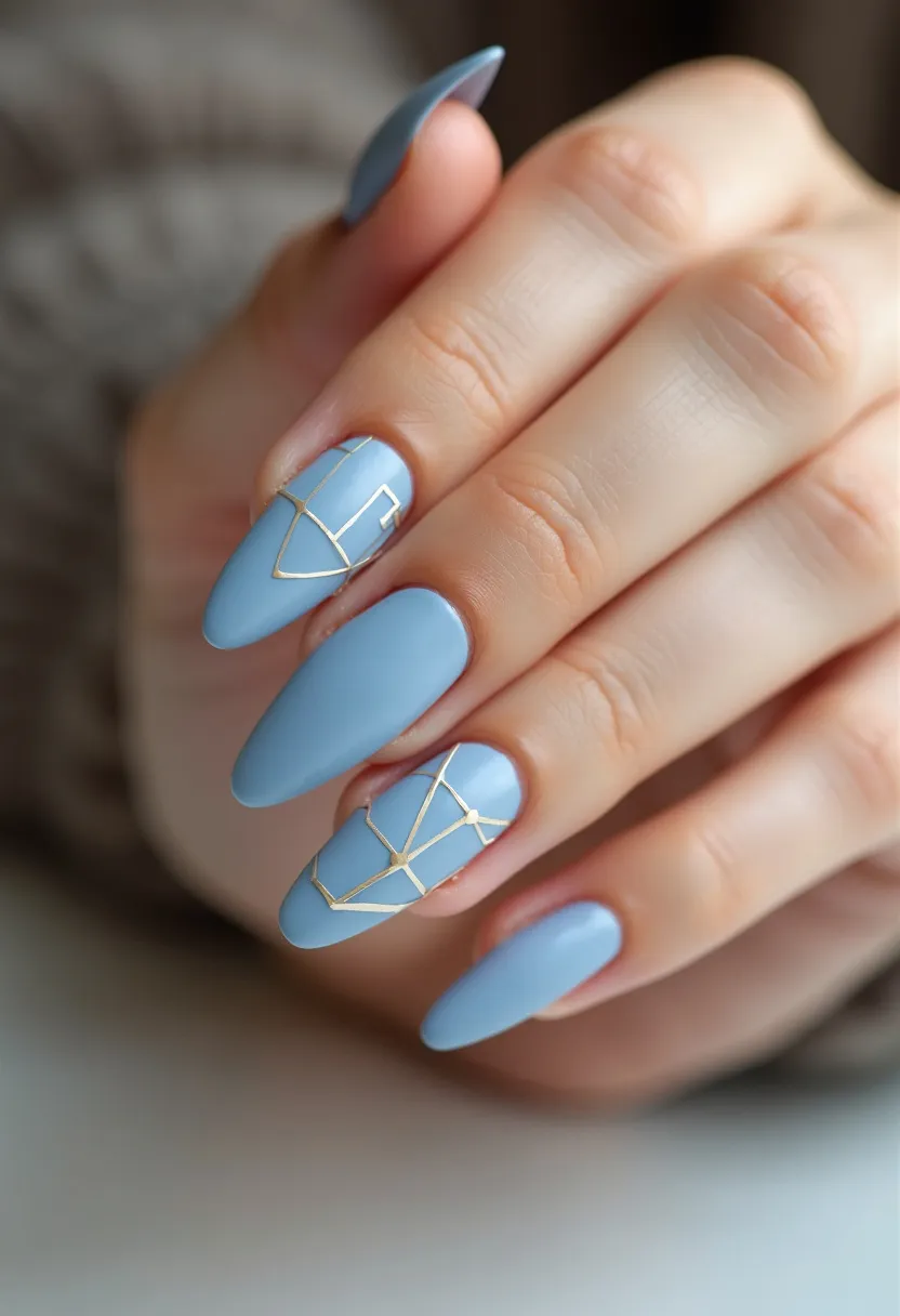 The nail design features an elegant almond shape, with a sophisticated color palette predominantly in a soft, matte blue shade. Accentuating the blue base, intricate gold foil lines form geometric patterns on the ring and middle fingers, adding a modern and stylish touch to the design. This geometric decoration showcases a trendy and artistic approach, suggesting a potential application of gel or acrylic treatment for the precision and durability observed. The refined and clean look of this nail design may be suited for both everyday wear and special occasions, offering a chic yet understated choice that bridges versatility and elegance.