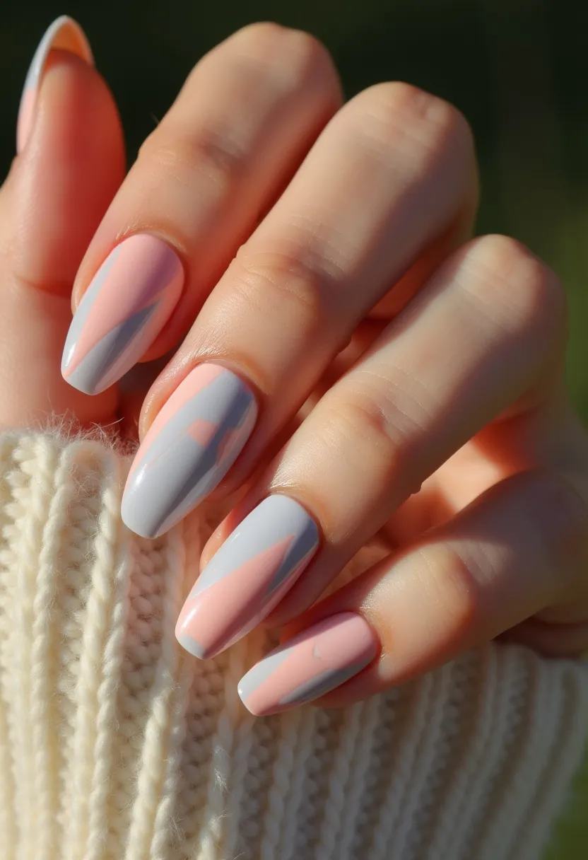 This nail design features a sophisticated color palette of soft pastel hues, primarily composed of light pink and pale gray. The nails are shaped into a rounded almond form, creating an elegant and elongated look. Intricate patterns adorn the nails, characterized by a combination of color blocking and geometric shapes that blend seamlessly together. The nail treatment appears to be gel-based, lending a high-shine finish and durable wear. Unique details include the harmonious interplay of the colors, with each nail showcasing a slightly different geometric design, suggesting a cohesive yet varied aesthetic. The gentle and soothing tones imply a versatile, season-neutral theme, suitable for various occasions, from casual day-to-day wear to more formal settings.