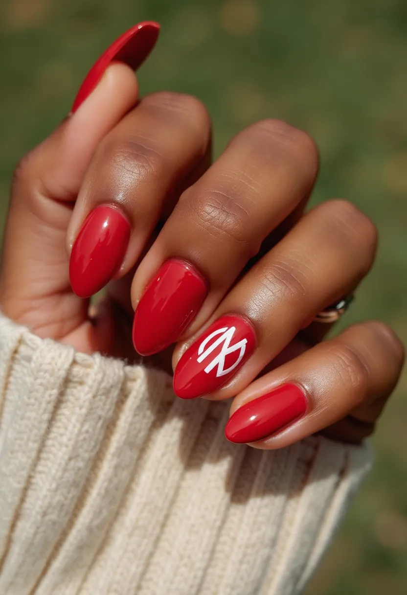 The nail design features a vibrant red color palette, emphasizing elegance and boldness. The nails are shaped in a tapered almond form, providing a sleek and modern aesthetic. Intricate detailing is present on the ring finger, which showcases a white graphic design that appears to be an abstract or stylized symbol, adding a unique and personal touch to the overall look. The glossy finish of the nail polish indicates a gel treatment, known for its durability and high-shine quality. The red and white combination can be associated with festive or seasonal themes, making it suitable for special occasions where a bit of flair is desired.