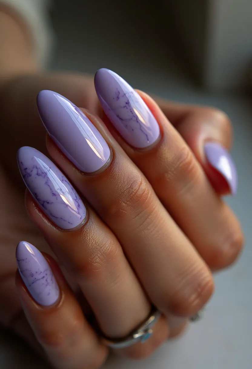 The nail design showcases an elegant almond shape, featuring a color palette dominated by a soft lavender hue. Each nail exhibits a high-shine finish, suggesting a gel or shellac treatment for a glossy, durable look. Some nails are adorned with delicate marbling patterns in a slightly darker lavender shade, adding a sophisticated and artistic touch to the design. The marbling effect gives the nails a unique, textured appearance, providing subtle complexity and making them suitable for both everyday wear and special occasions. This design has a gentle and serene aesthetic, making it a perfect choice for spring or early summer seasons.