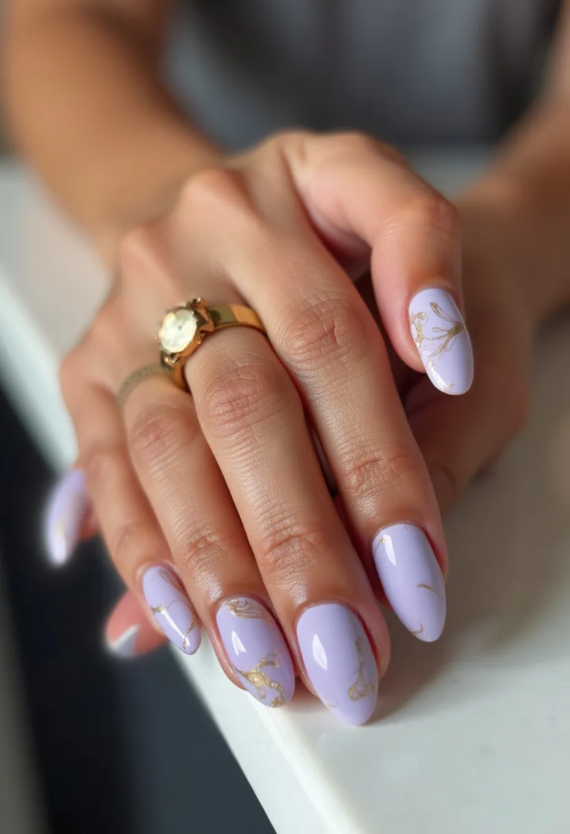 The nail design showcases a sophisticated lavender color palette with accents of gold patterns, creating an elegant and refined look. The nails are medium-length with a rounded oval shape, contributing to a soft and feminine appearance. Additionally, the nails exhibit intricate gold foil designs that resemble delicate floral or vine motifs, adding a touch of intricacy and luxury to the manicure. This design appears to be done with gel polish, considering the glossy finish and the smooth texture of the nails. These nails would be perfect for a spring or summer occasion due to the light and fresh color scheme, and the elegant gold decorations make them suitable for special events or celebrations.