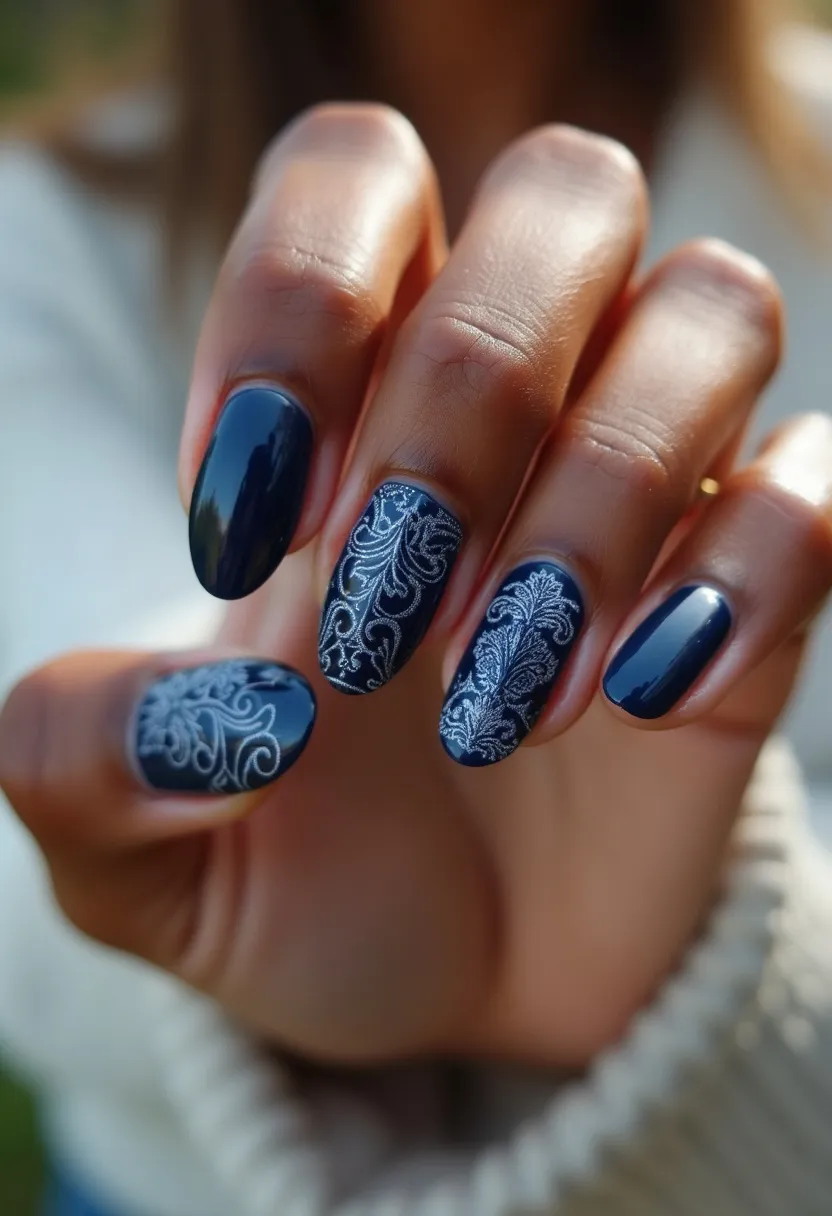 The nail design features a sophisticated color palette dominated by a deep navy blue base, exuding elegance and style. The nails are shaped in a medium-length oval form, enhancing their chic and versatile appearance. Adorning some of the nails are intricate white floral patterns, intricately detailed and symmetrically positioned, creating a striking contrast against the dark base. The design suggests a gel or acrylic nail treatment due to its glossy and smooth finish. This nail art is suitable for a special occasion, possibly a formal event or a festive season, thanks to its ornate and refined detailing.