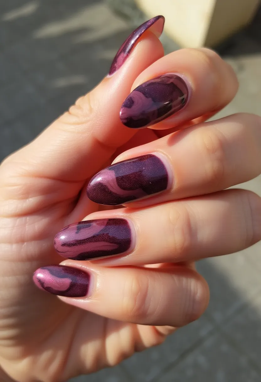 The nails in the design feature a stiletto shape, characterized by their elongated and pointed tips. The color palette predominantly includes deep shades of purple and burgundy, with a shimmering finish that suggests the use of a gel treatment for added gloss and durability. Intricate marbled patterns are present on each nail, blending dark and light hues of the primary colors to create a swirling, almost smoky effect. This design lends itself to a sophisticated and elegant aesthetic, making it suitable for special occasions or complementing autumn and winter seasonal themes with its rich and warm tones.