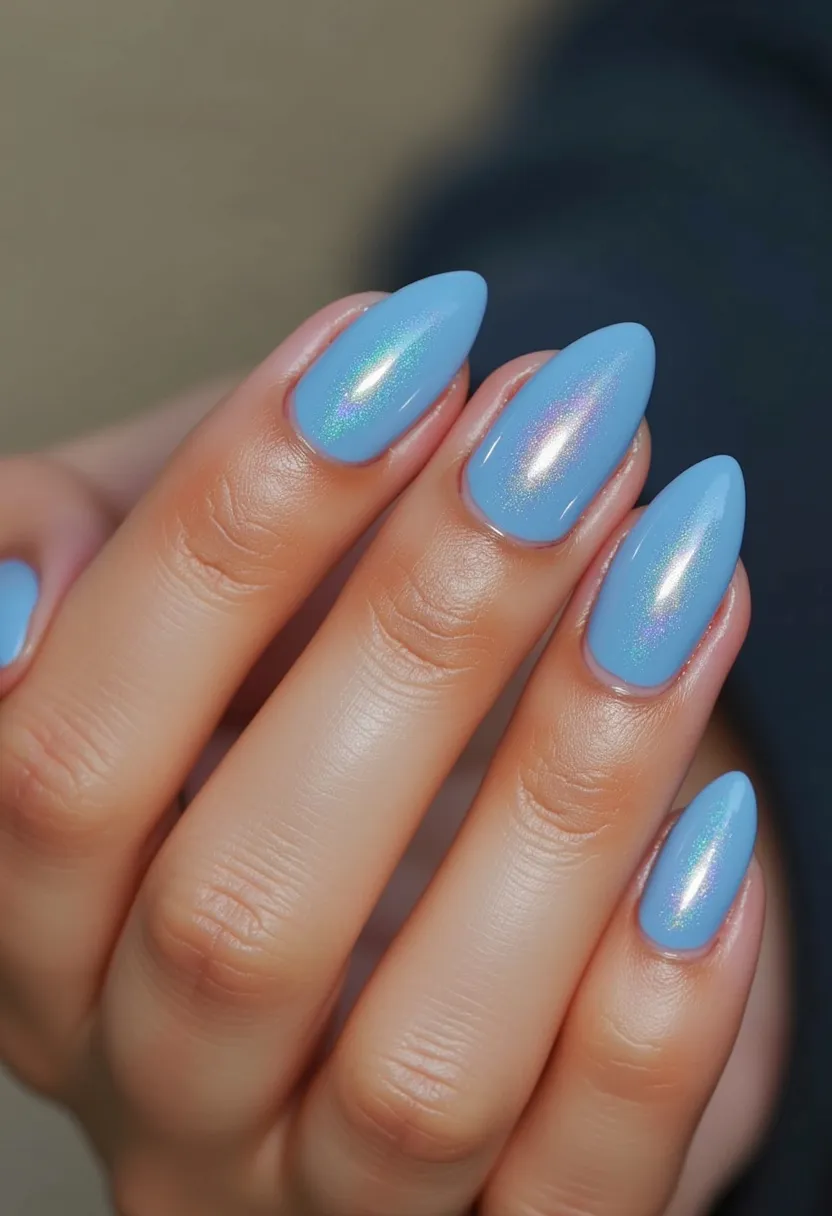 The nails are shaped in a stiletto style with a long and pointed tip. The color palette primarily features a light blue base with an iridescent shimmer, giving a holographic effect that reflects shades of pink and purple. The nail treatment appears to be a gel polish, known for its glossy and smooth finish. The design is sleek and sophisticated, with no additional intricate patterns or decorations, allowing the iridescent finish to stand out. The overall look is fresh and modern, ideal for a spring or summer theme, though versatile enough for various occasions.