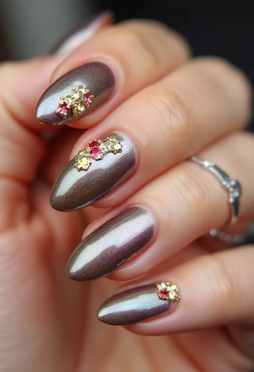 The nail design features an elegant combination of metallic hues, predominantly shades of iridescent bronze and shimmer that give a sophisticated and reflective look. The nails are sculpted into a classic almond shape, providing a refined and elongated appearance. They are adorned with clusters of small, intricate decorations, which include gold embellishments and tiny rhinestones in colors such as ruby red and light yellow, arranged near the cuticle area of each nail. This design seems to make use of gel polish, offering a smooth and glossy finish. The rich color palette and luxurious accents suggest a festive or celebratory theme, suitable for special occasions like holidays or formal events.