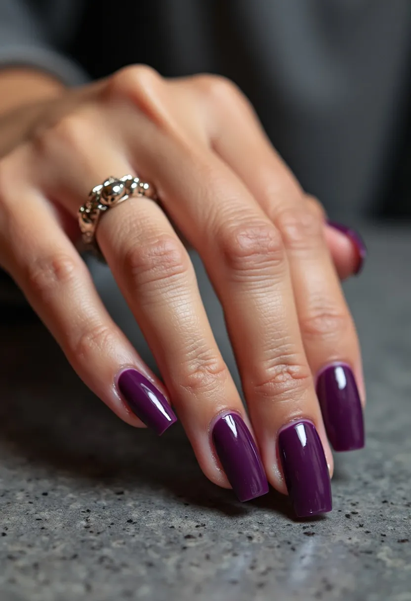 The nail design showcases a rich, deep plum color palette that exudes sophistication and elegance. The nails are shaped into a medium-length squared form, providing a classic and well-defined silhouette. A glossy finish suggests the use of gel treatment, enhancing the color's intensity and adding a sleek, polished look. The design is minimalistic, without any additional patterns or decorations, which emphasizes the boldness of the single color choice. This nail design appears versatile but could be particularly fitting for the autumn season or elegant evening events, thanks to its timeless and refined appeal.