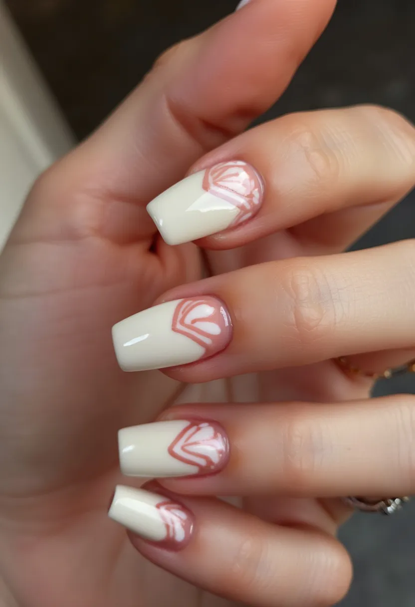 The nails are designed in a square shape with a sophisticated and elegant look, adopting a color palette that combines a creamy off-white with subtle pinkish-beige accents. The nails appear to have a glossy finish, indicating possible use of gel or shellac nail treatment for added durability and shine. Each nail features an intricate, delicate pattern resembling the art deco style, drawn in the same pinkish-beige shade at the nail bed, giving the appearance of a fan or shell. This design adds a touch of artistic flare while maintaining a minimalist and classy aesthetic, suitable for any season or special occasion.